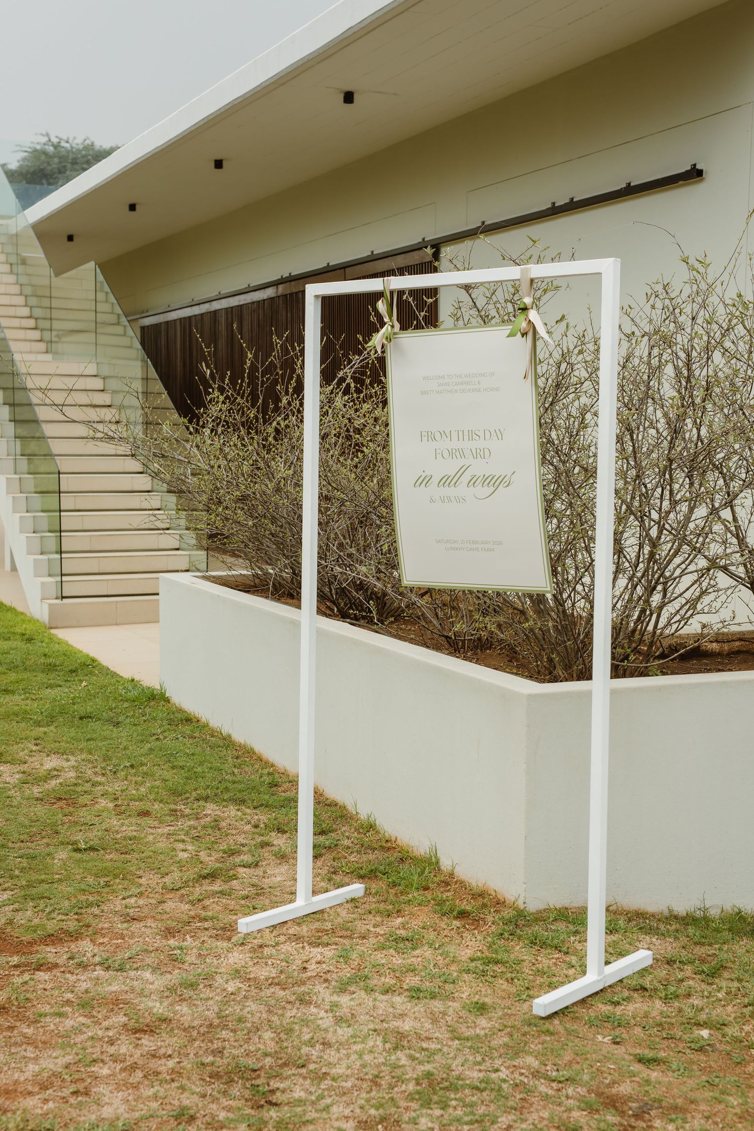 White decorative signs line a walkway outside a modern building with clean architectural lines.
