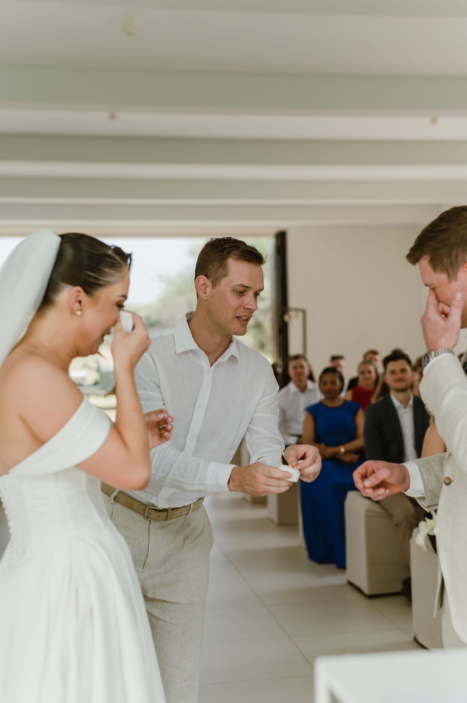 Emotional moment during wedding ceremony as couple and officiant share laughter while guests look on.