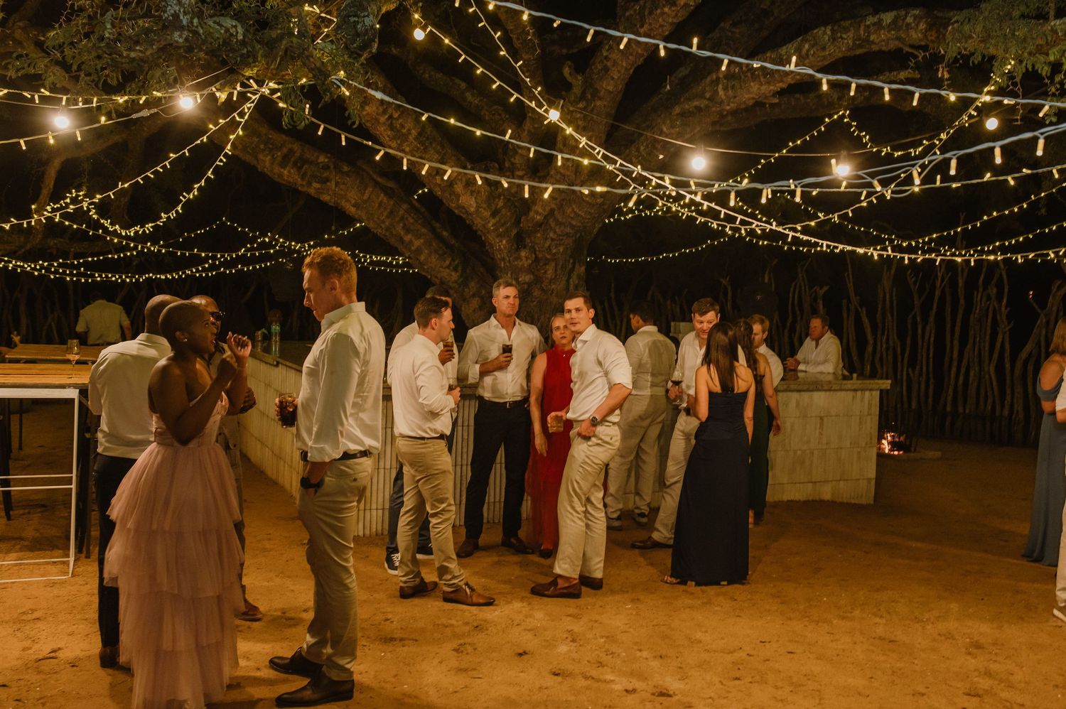 String lights create a magical canopy over an outdoor wedding reception space.