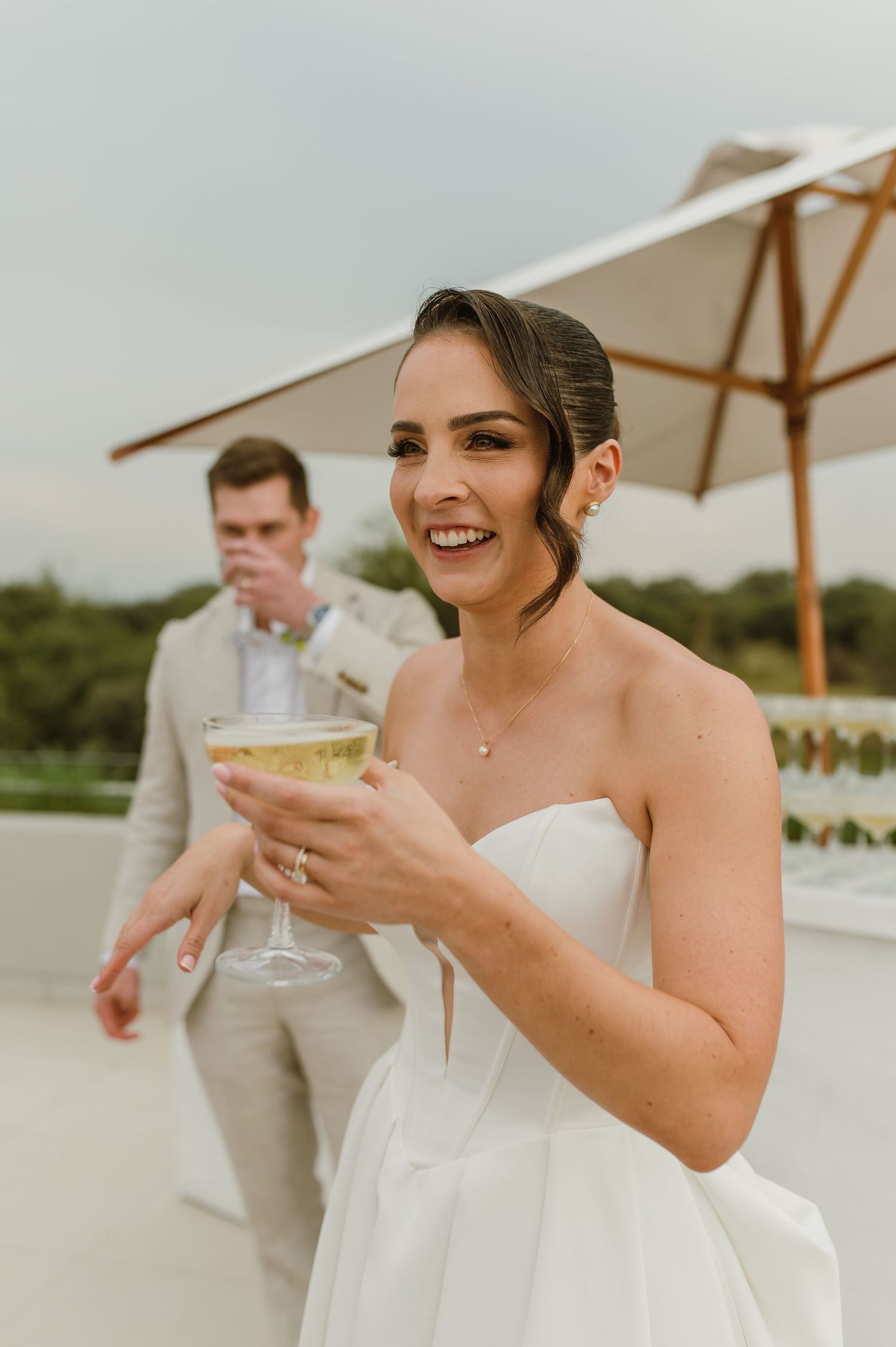 Celebration on an outdoor terrace with guests enjoying cocktails under white umbrellas.