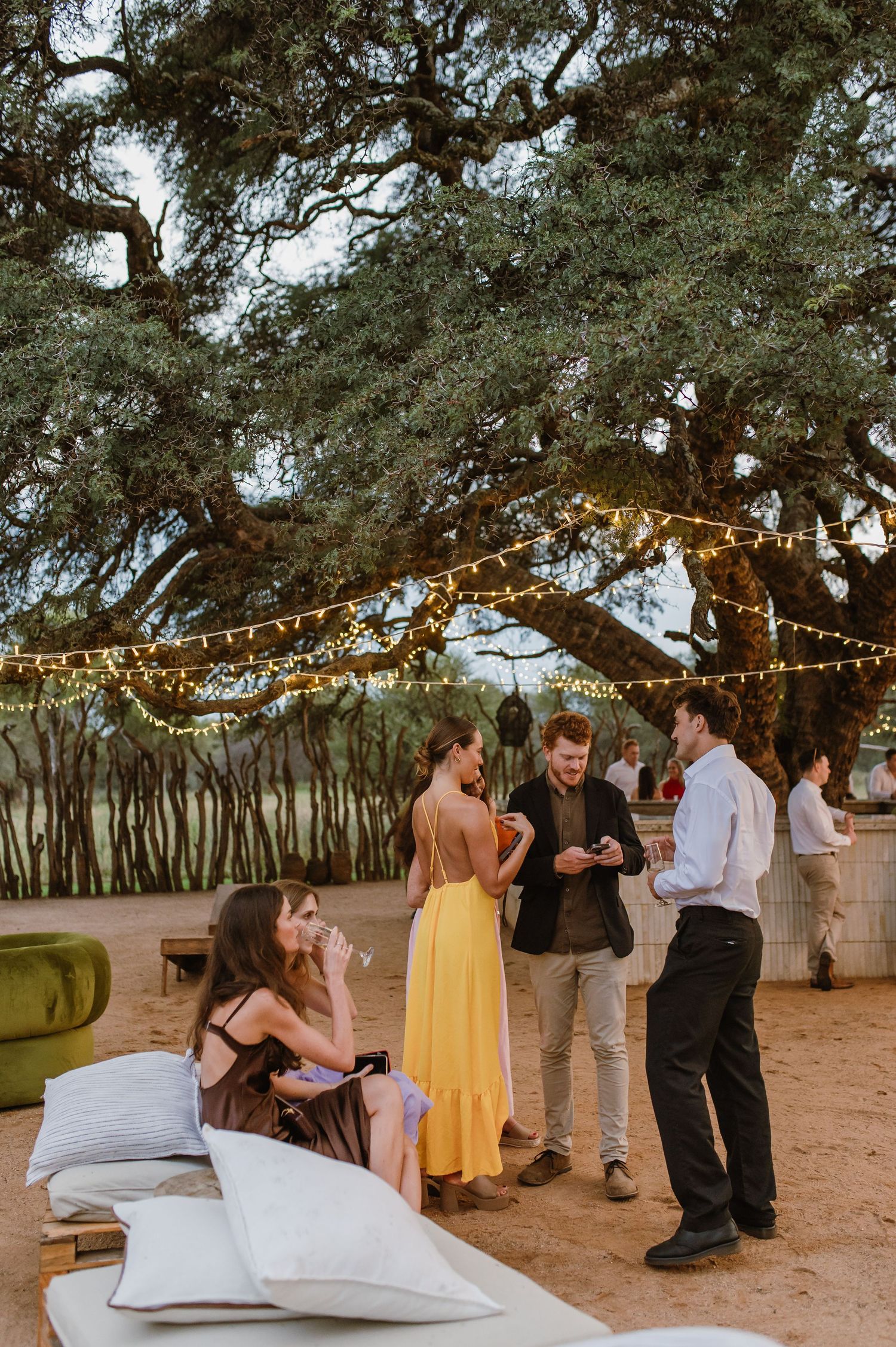 Wedding guests dance and celebrate under string lights at an outdoor reception venue.
