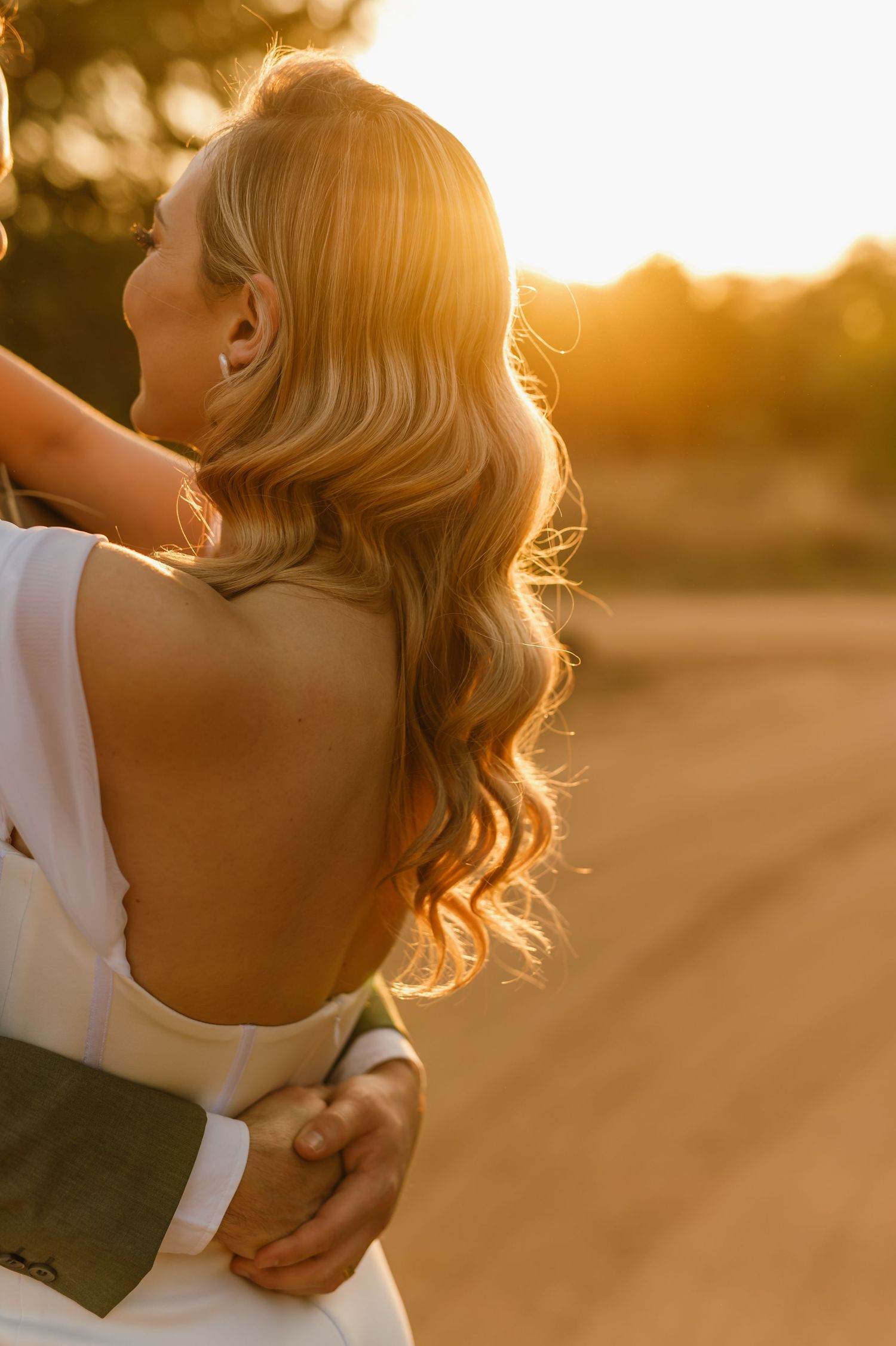 Golden hour sunlight illuminates a couple's tender embrace outdoors.