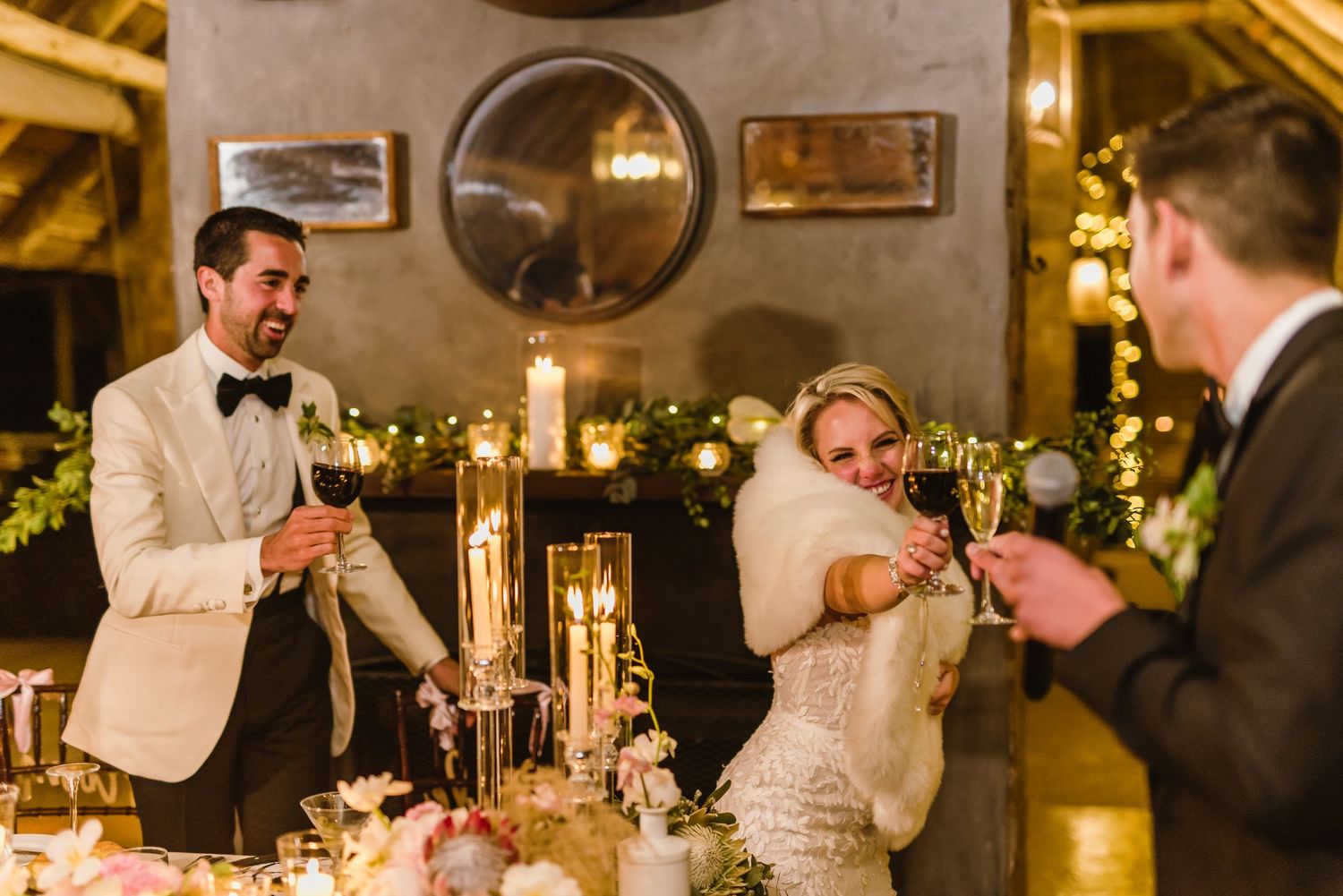 Celebratory moment at the wedding reception head table with elegant place settings and decor.