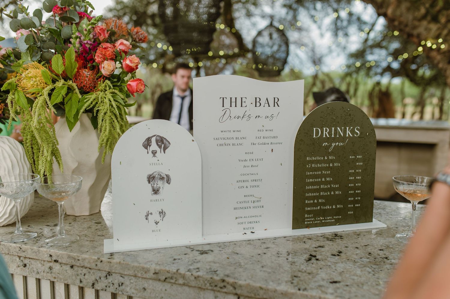 Wedding bar menu displays and signage decorated with floral arrangements.