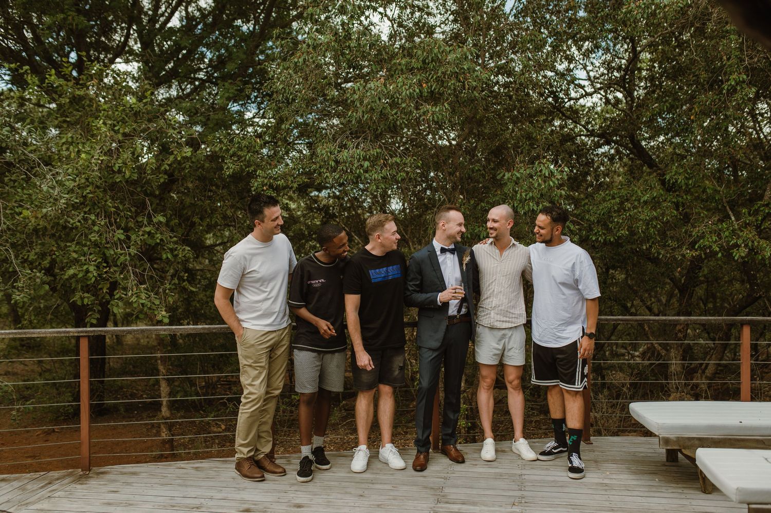 People gathering on a wooden deck surrounded by lush greenery.