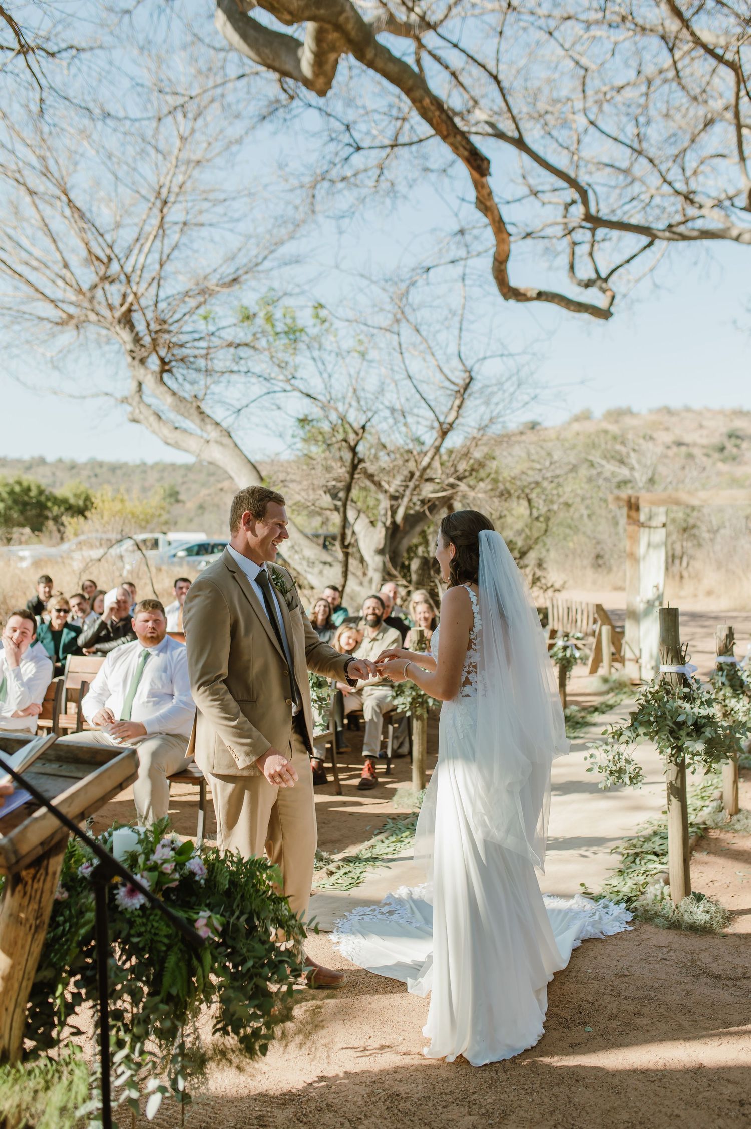 Wedding ceremony setup in a desert landscape with bare trees and white chairs.