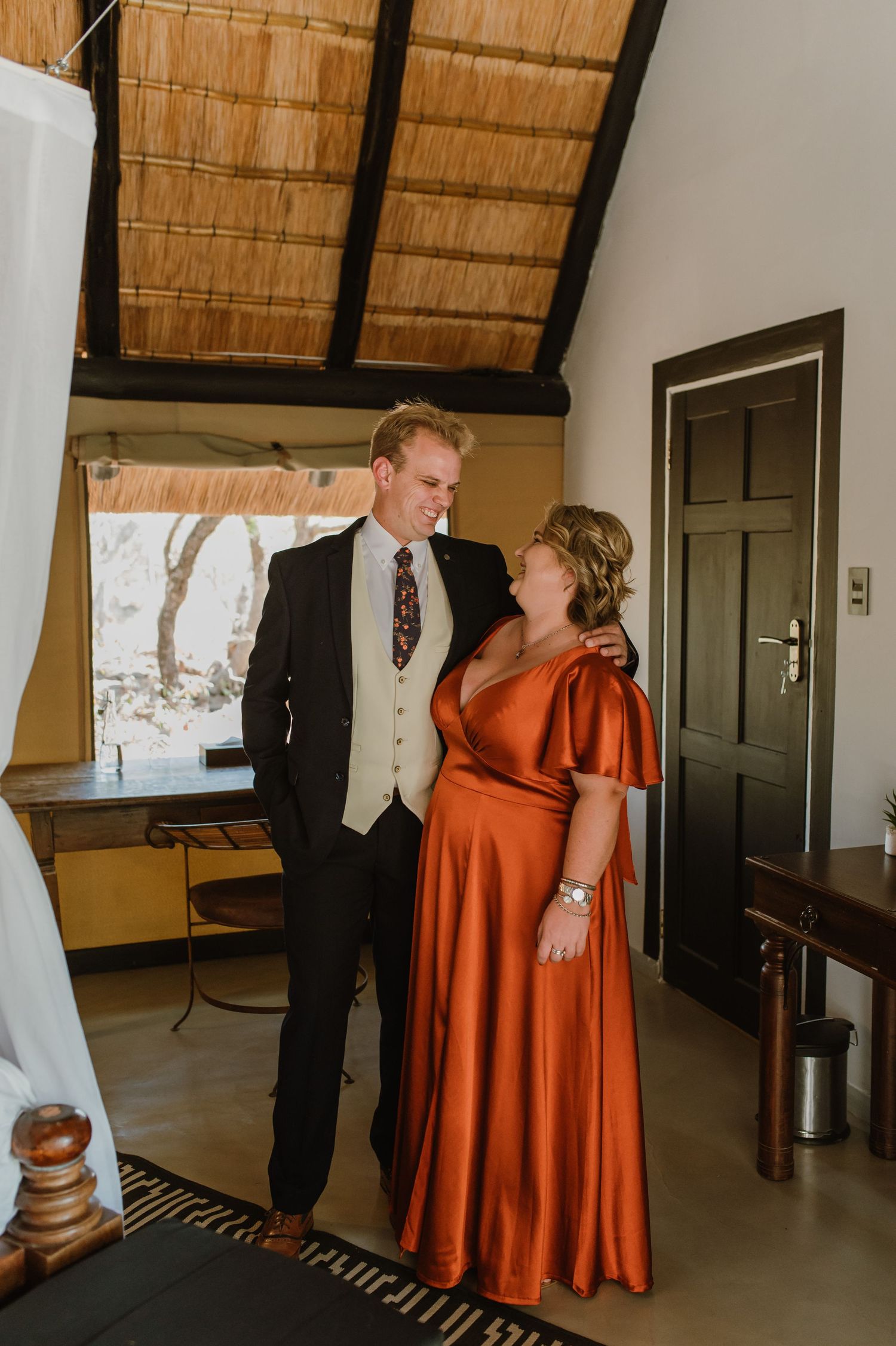 Two people in formal attire share a moment in an elegantly decorated room.