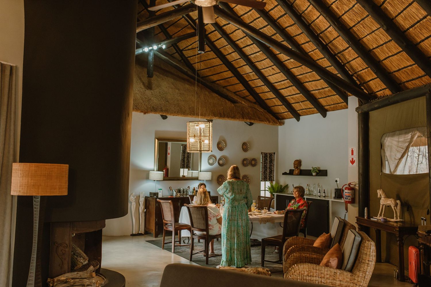 Rustic interior of a lodge with exposed wooden beams and thatched roof showing cozy seating arrangements.
