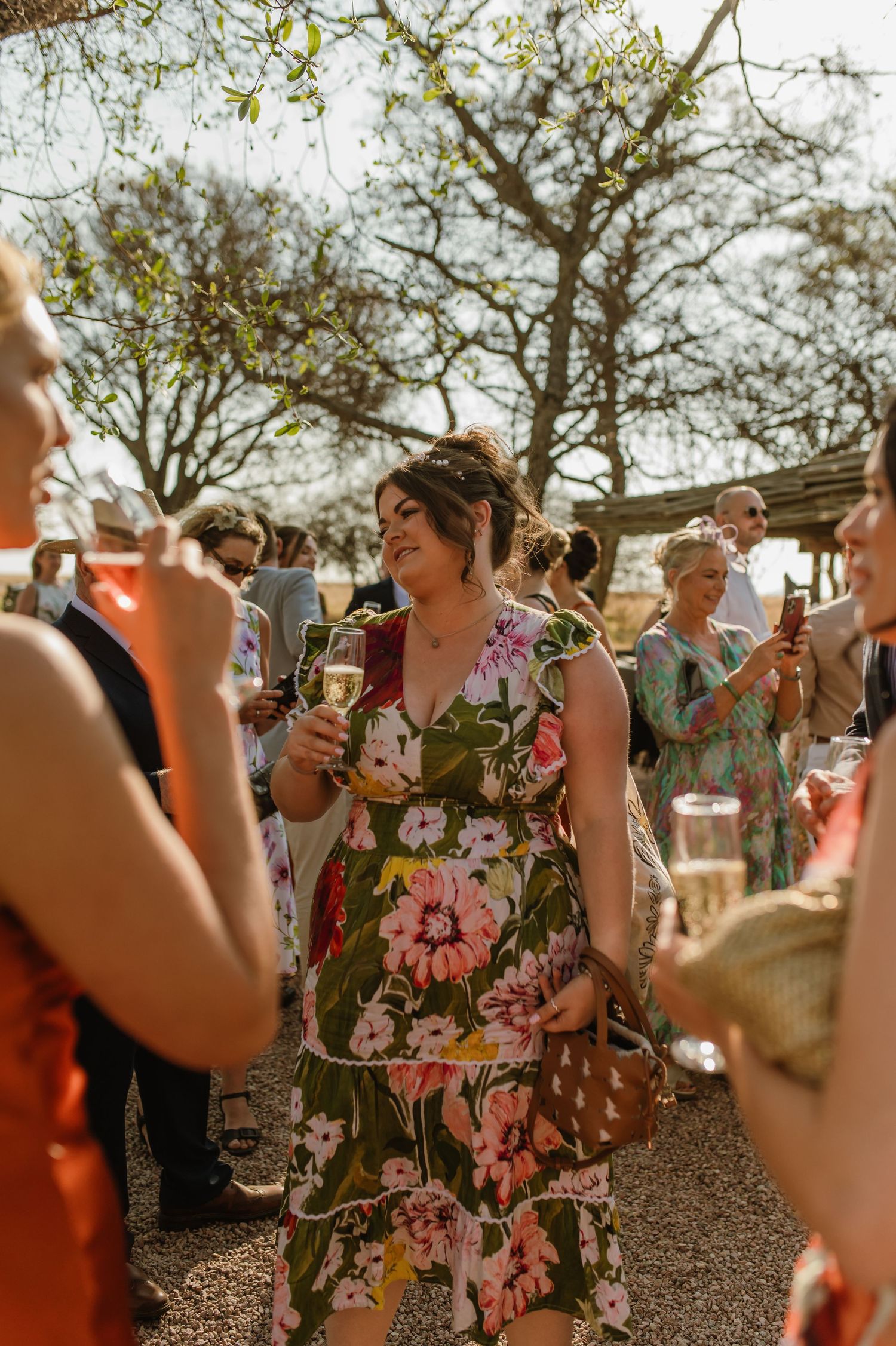 Wedding guests raise glasses for a toast during outdoor celebration.