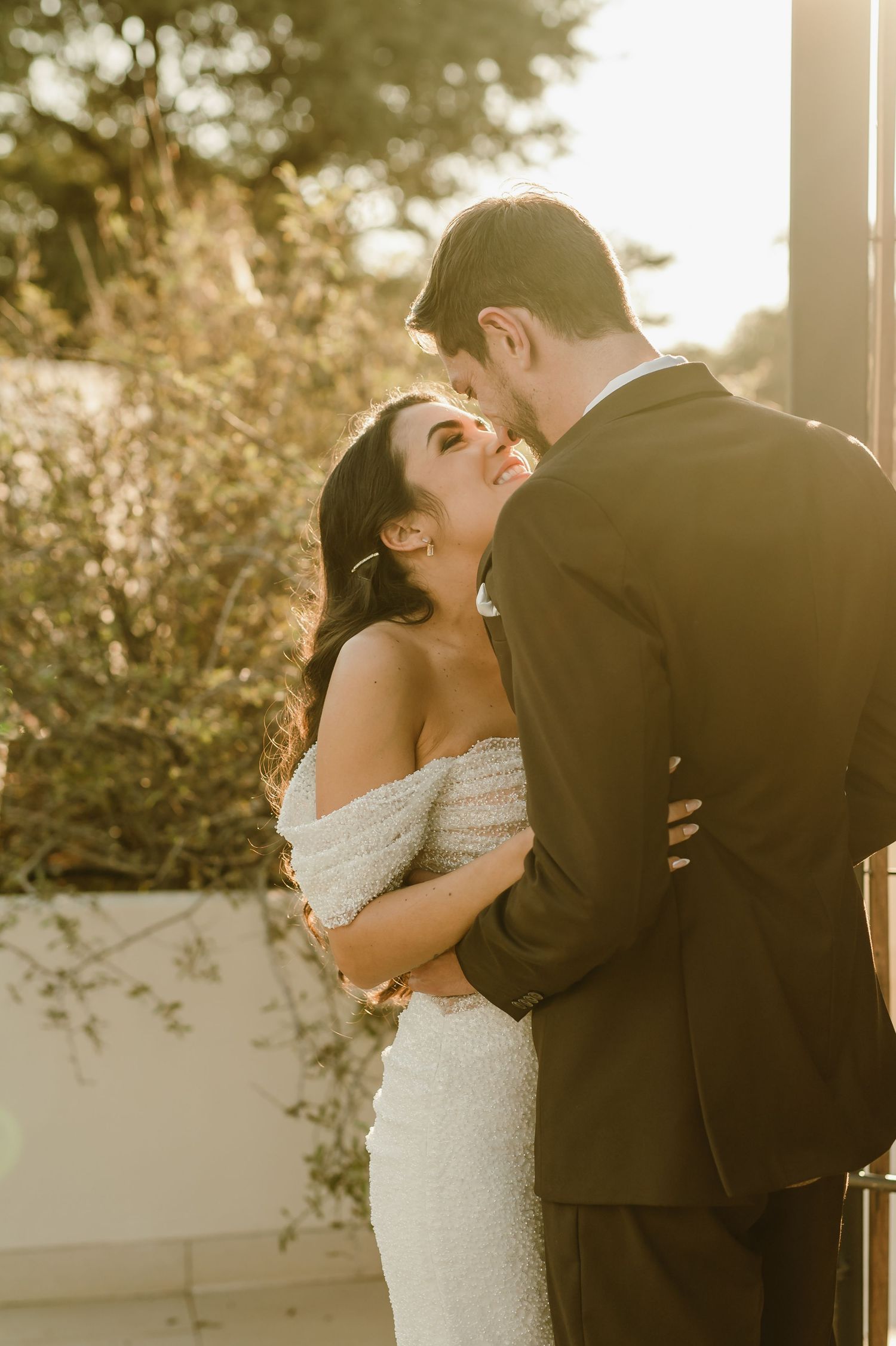 Romantic golden hour portrait of couple sharing intimate moment outdoors.