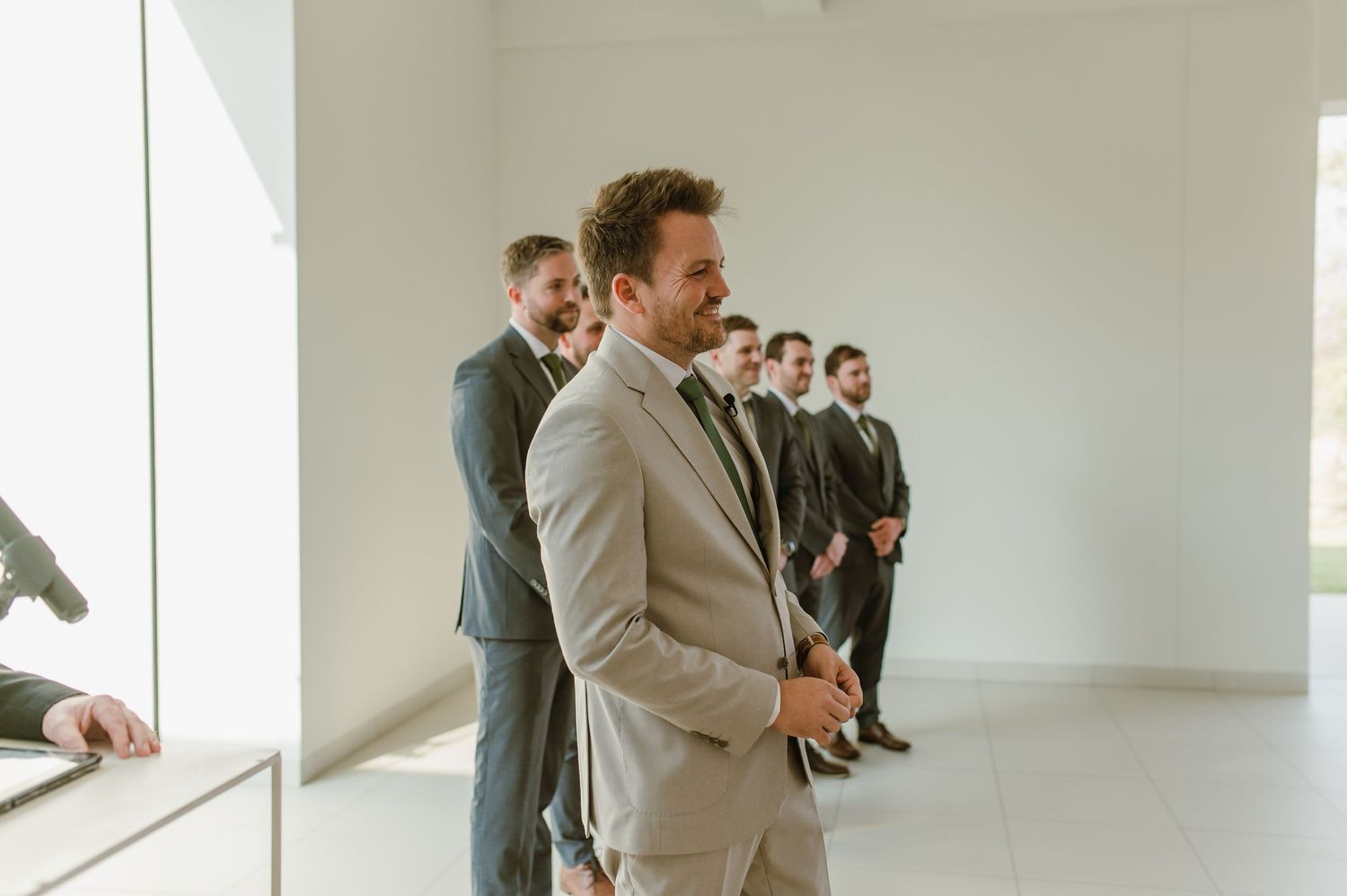 Wedding party members stand in a bright minimalist room with white walls.