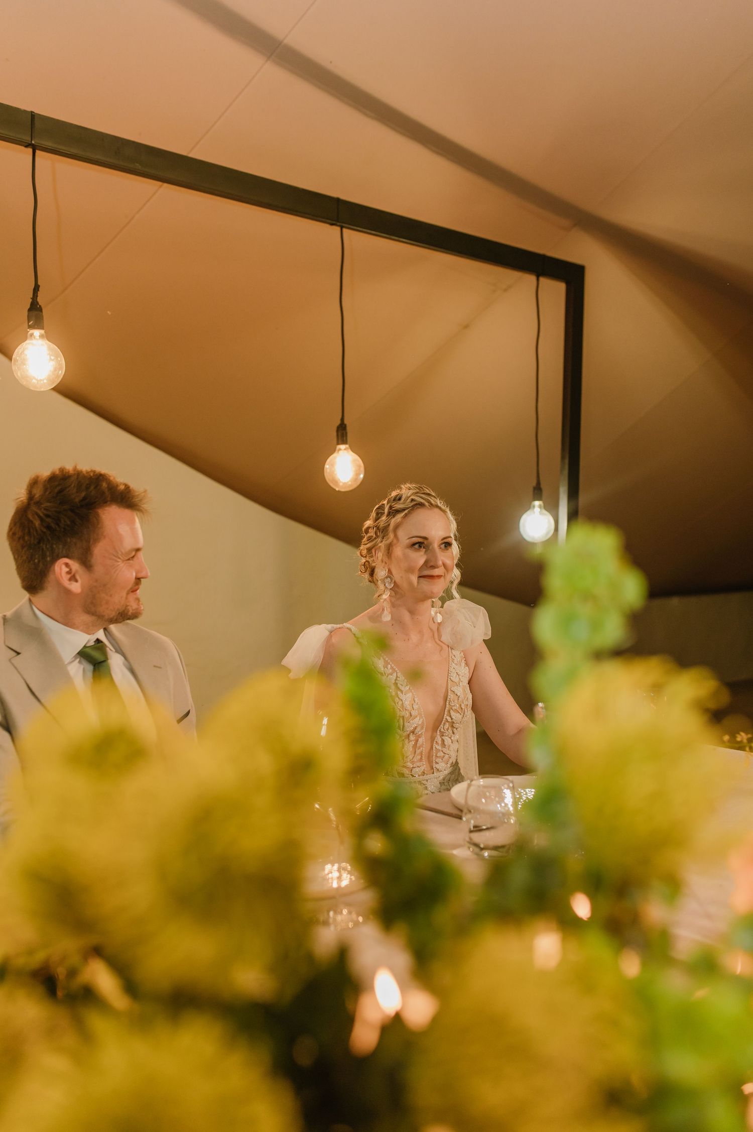 Intimate dining moment captured during wedding reception with soft lighting and floral decor.