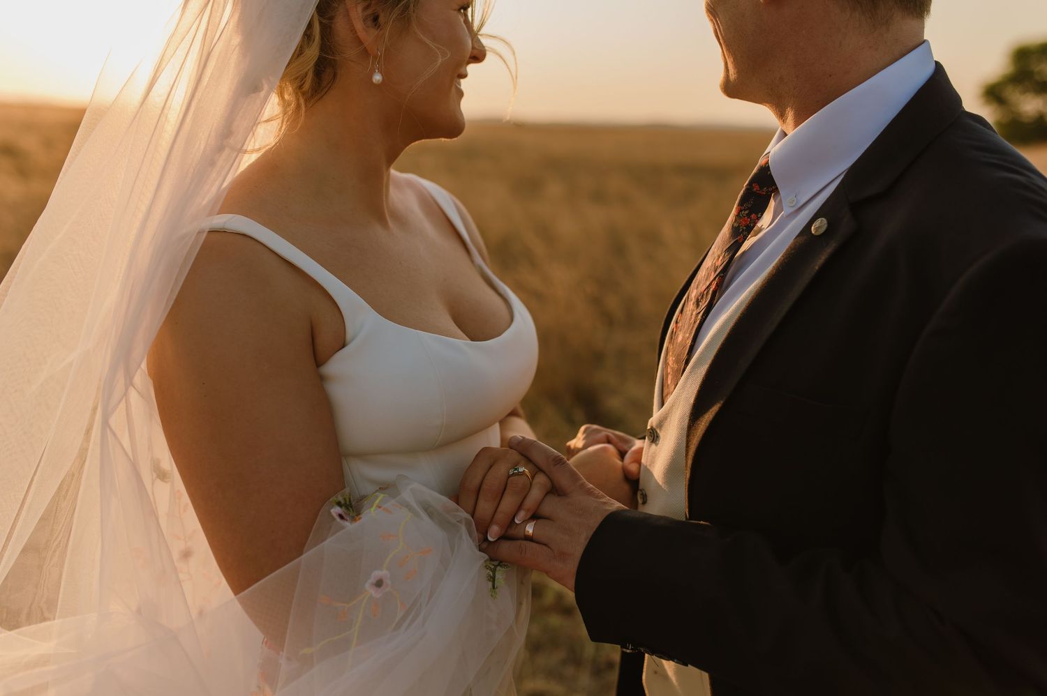Romantic wedding portraits in field during sunset with dramatic lighting.