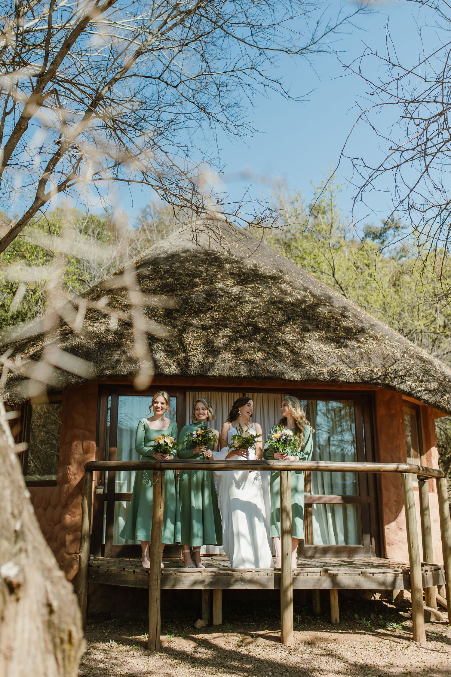 Rustic thatched-roof lodge surrounded by trees in natural setting.