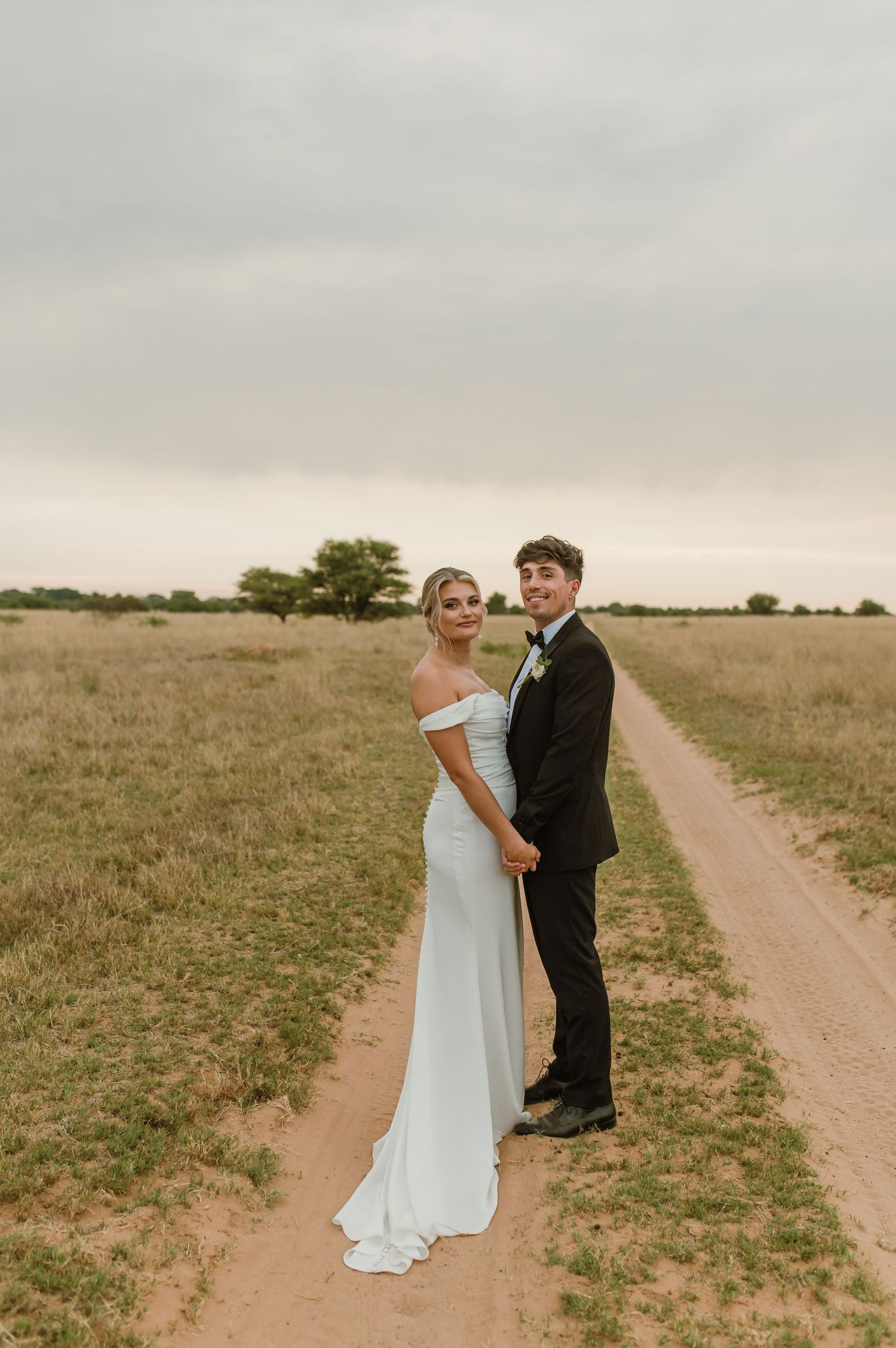 Warm-toned wedding photos of a couple sharing intimate moments on a rural dirt path.