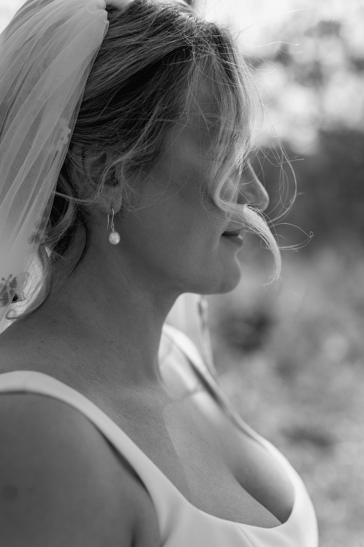 Side profile portrait of bride in elegant white dress with pearl earrings.