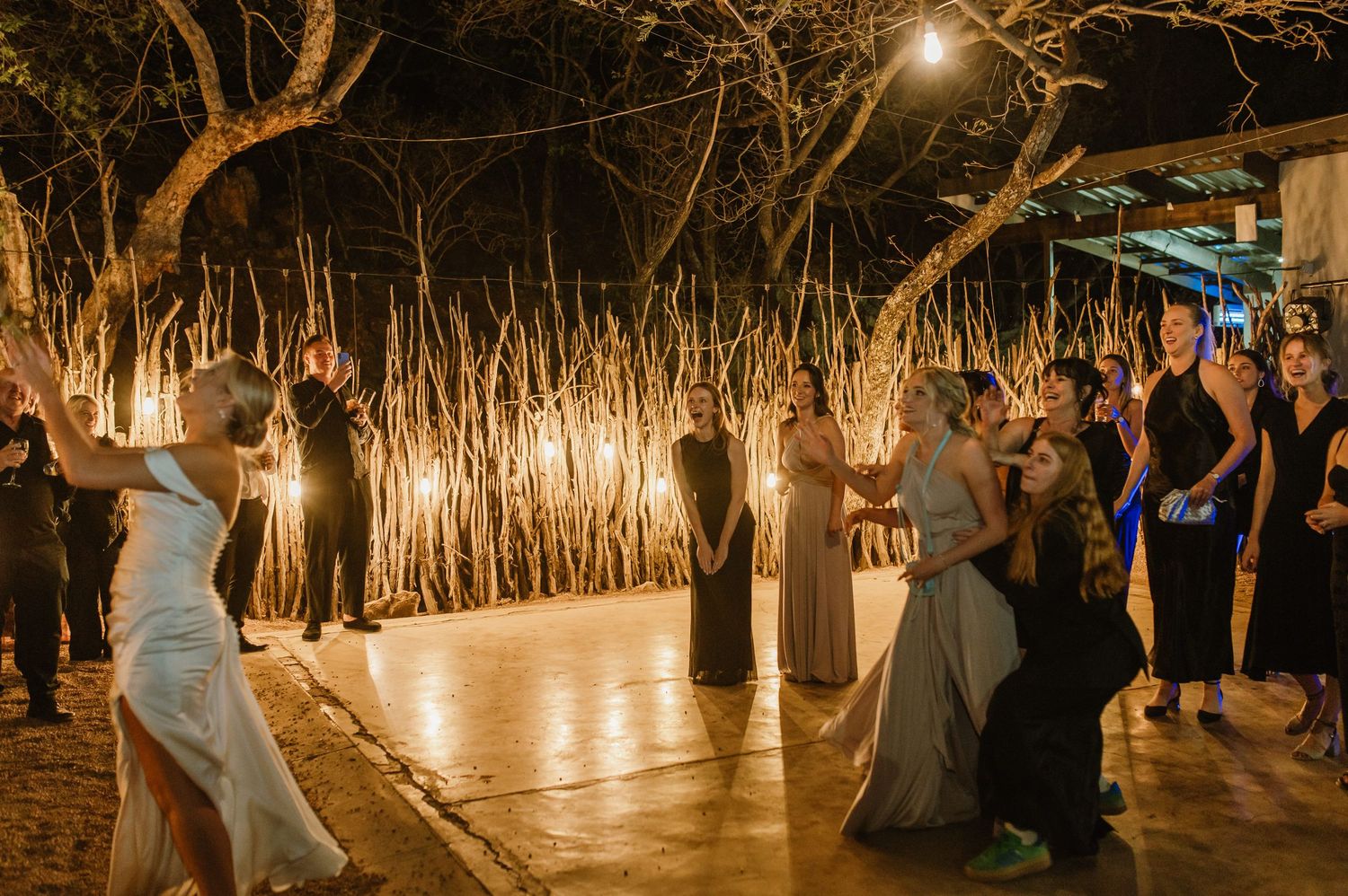 Evening reception venue decorated with hanging lights and natural branch elements.