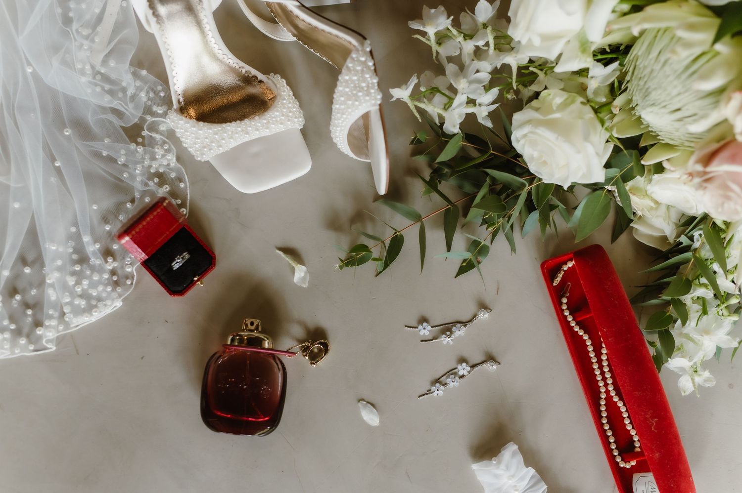 Wedding accessories including perfume, jewelry box, and white floral bouquet.