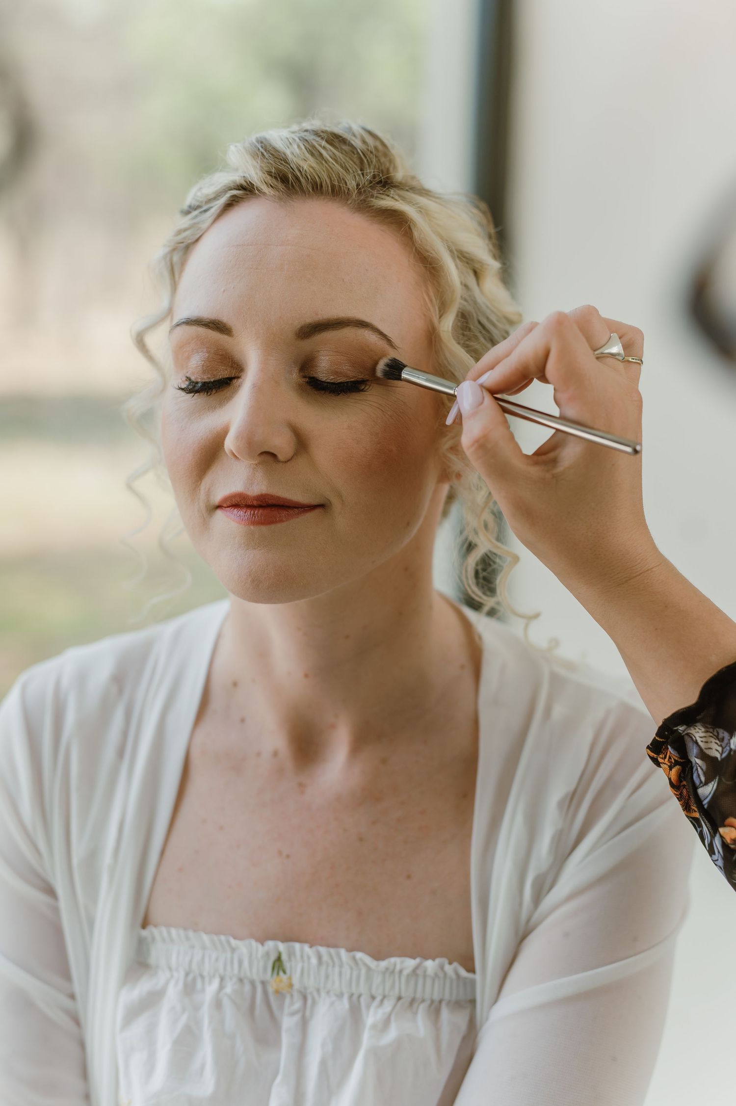Close-up sequence of makeup being applied with brushes during wedding preparation.