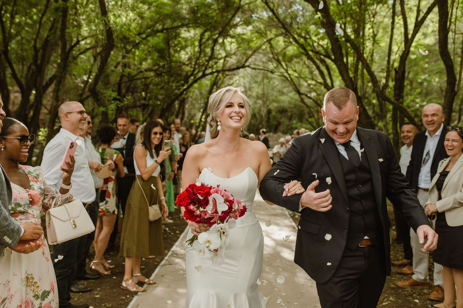 Wedding celebration captured in a series of candid moments along a forest walkway.