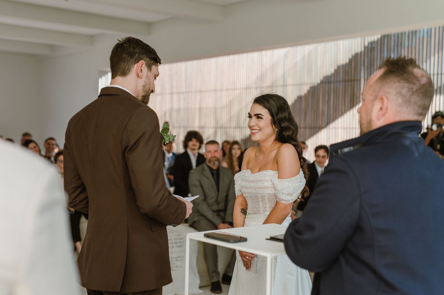 Wedding party members gather in a contemporary white-walled venue space.