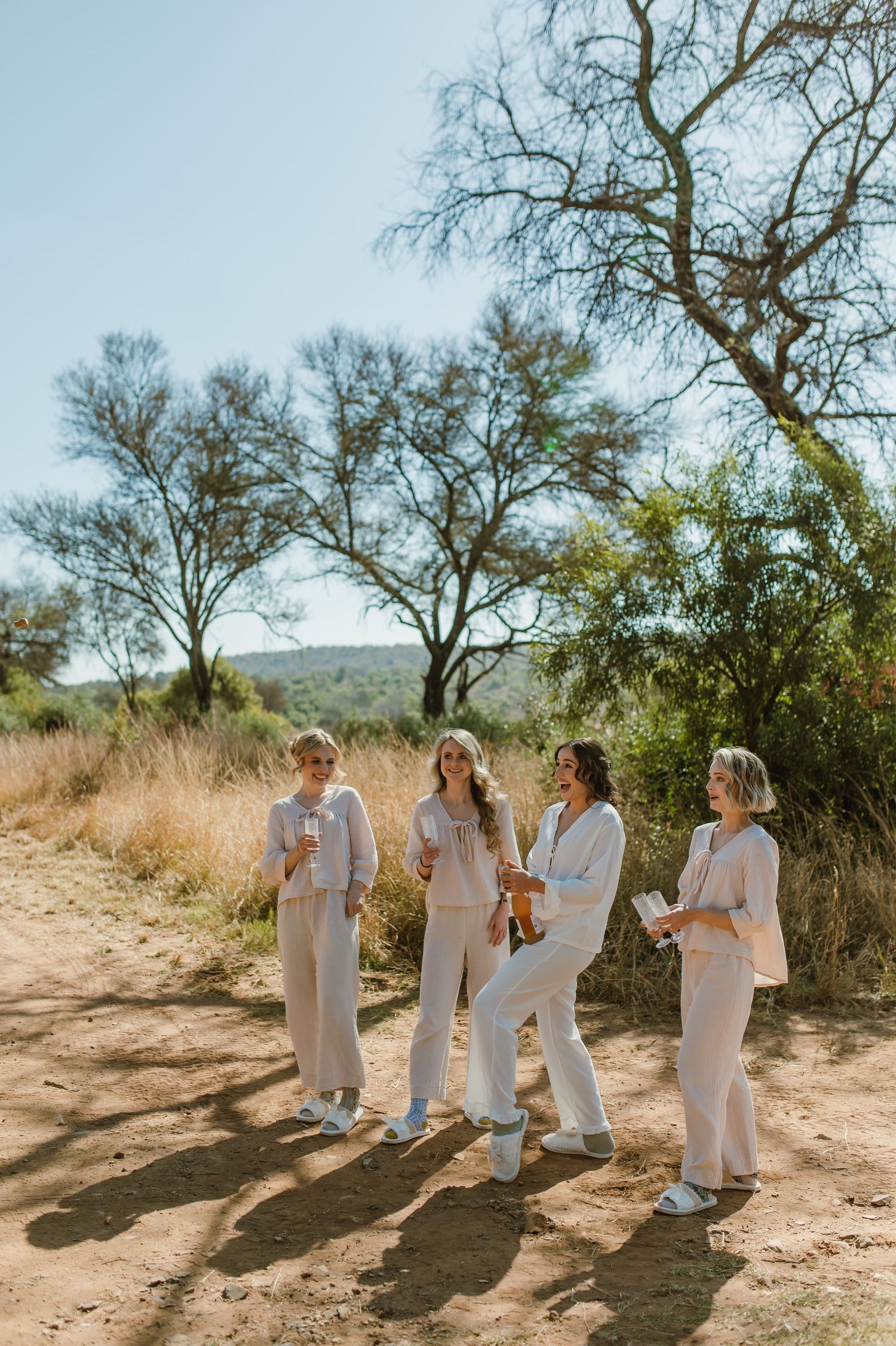 Group in white outfits walking together on desert path under bare trees.
