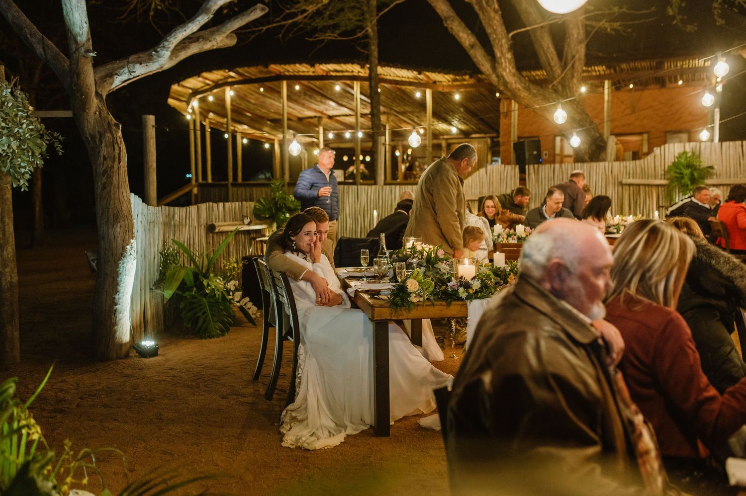 Wide view of a rustic barn wedding reception with string lights and wooden architectural details.