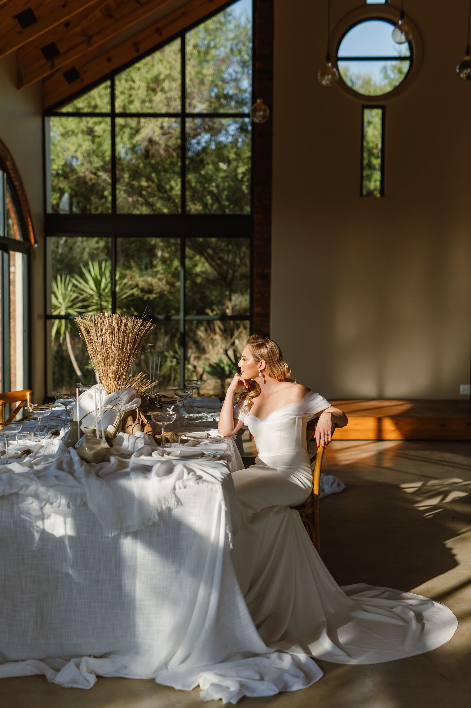Sunlit wedding reception setup with white linens and natural decor elements.