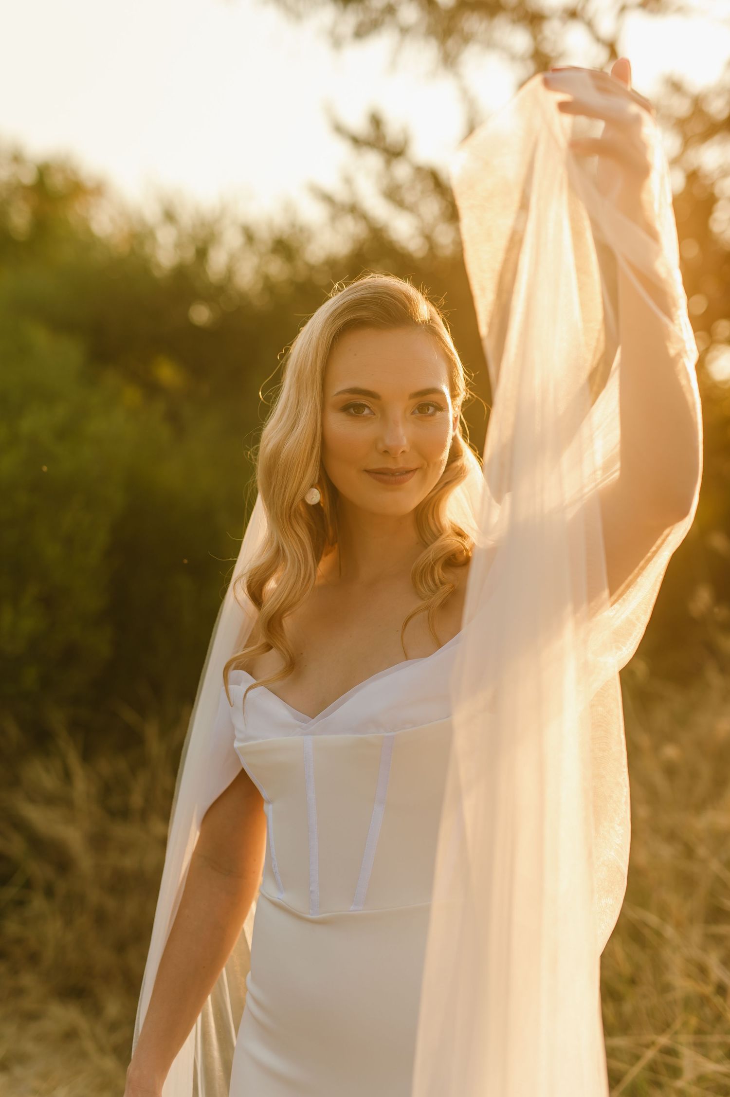 Elegant bridal portrait in soft golden light showing details of a classic white wedding dress.