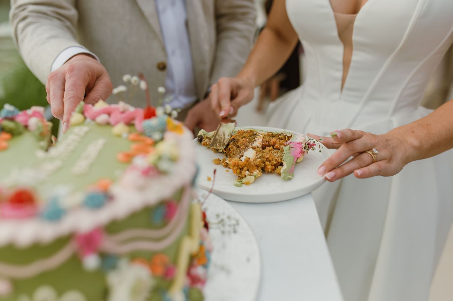 Close-up of hands serving food on decorative plates at an outdoor event.