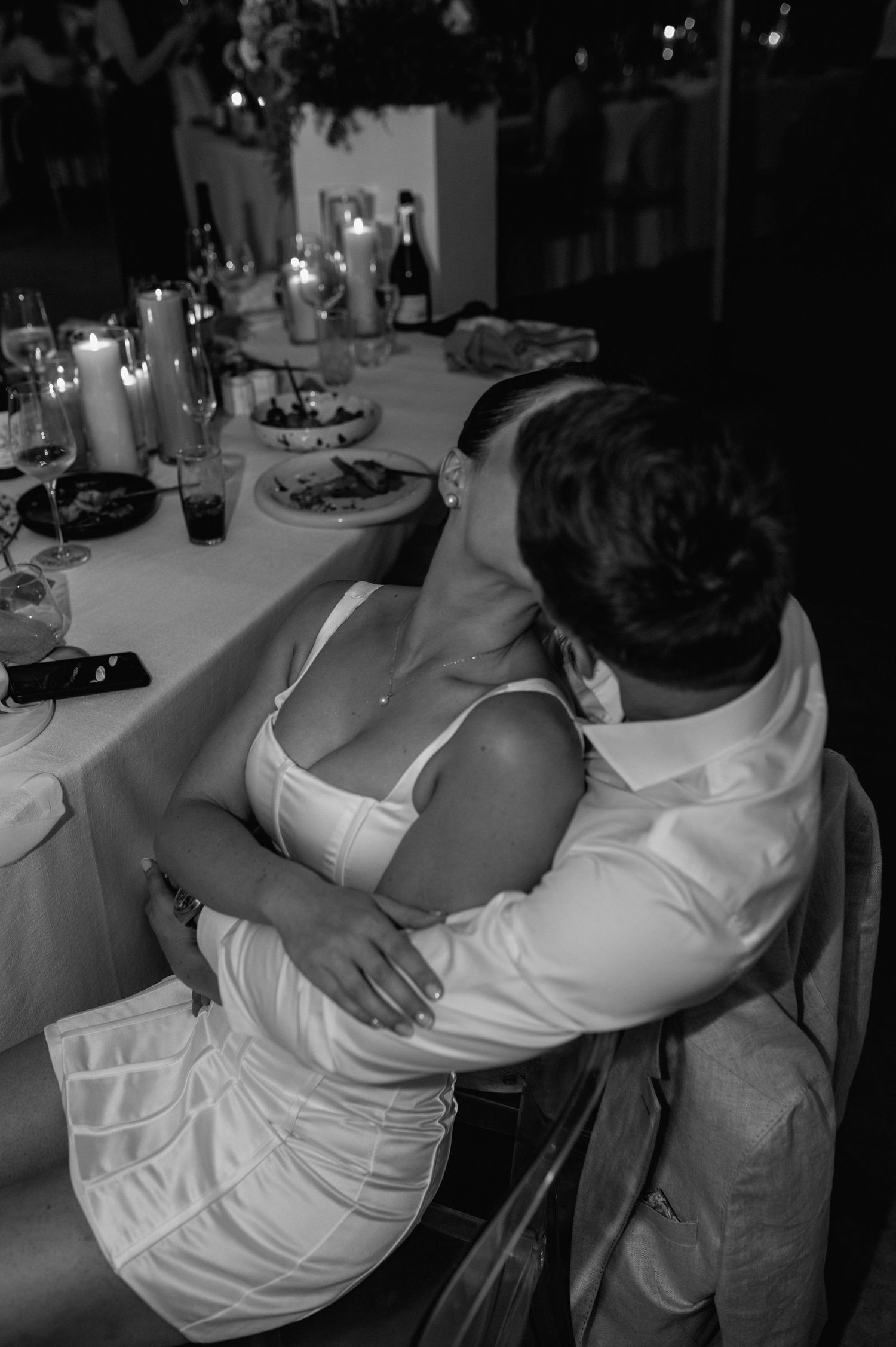 Intimate black and white moment at an elegant wedding reception dinner table.