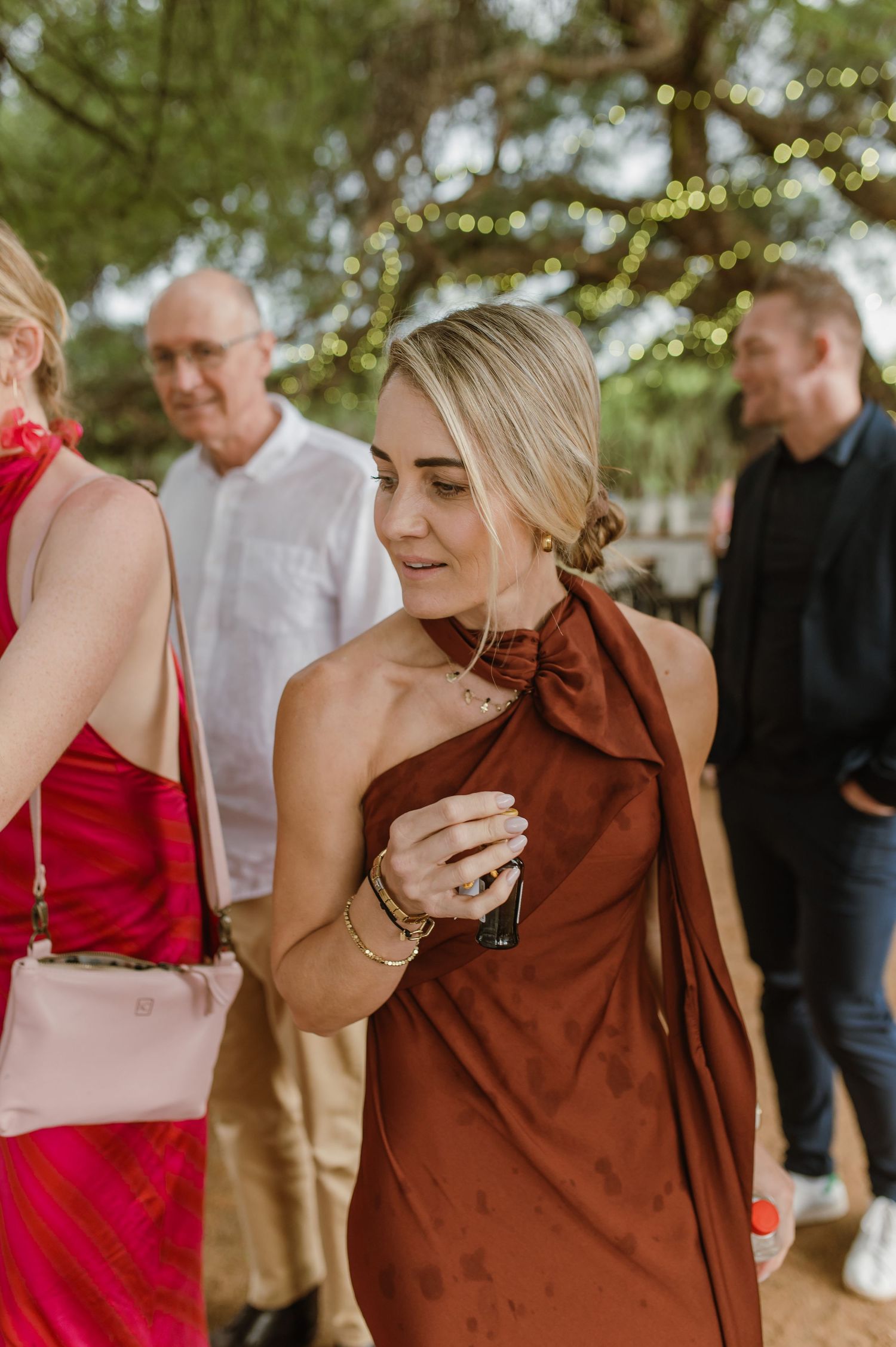 Wedding attendees in red and brown attire share emotional moments during an outdoor celebration.