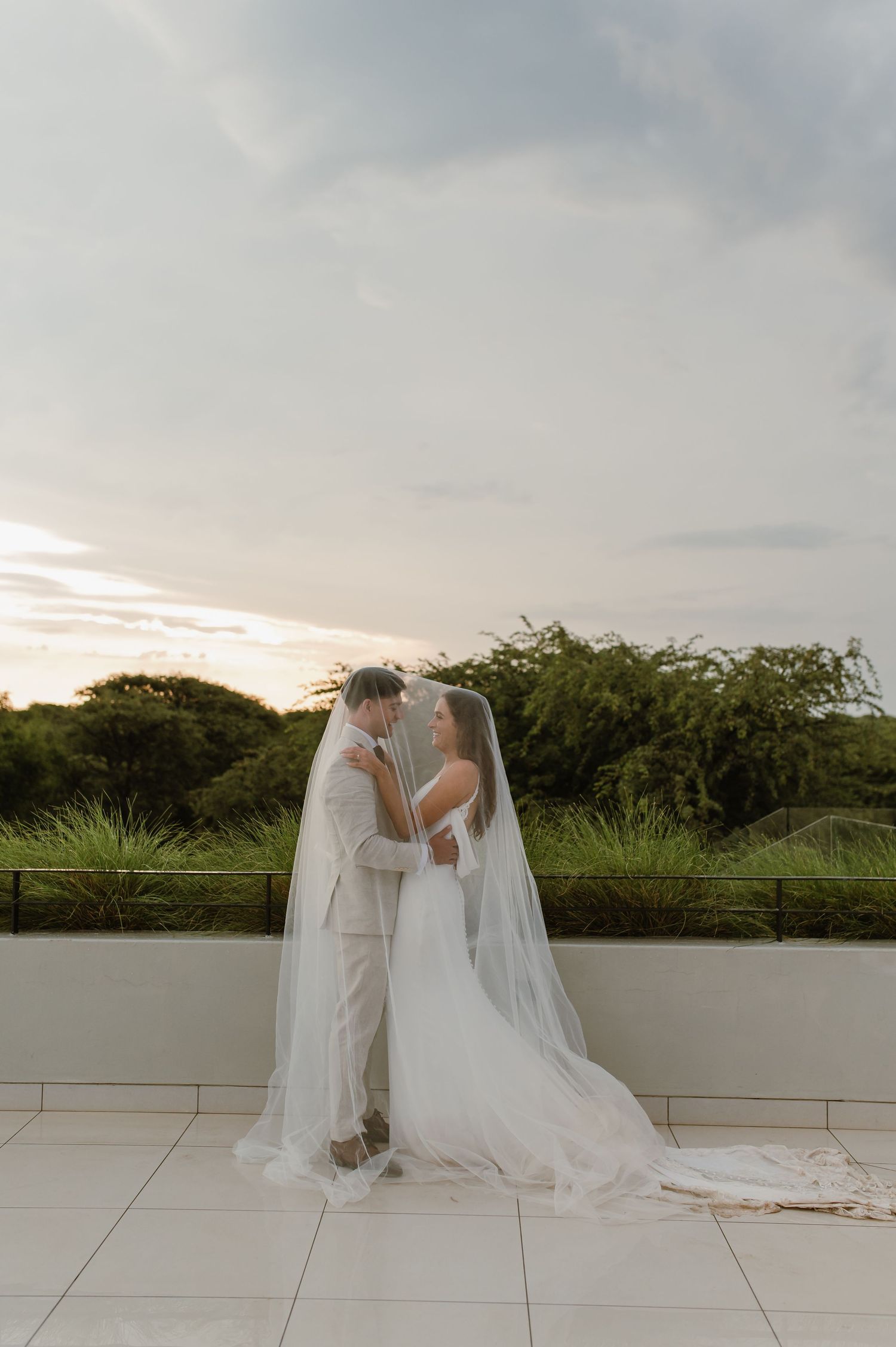 Wedding couple shares tender moment at sunset on tiled terrace.