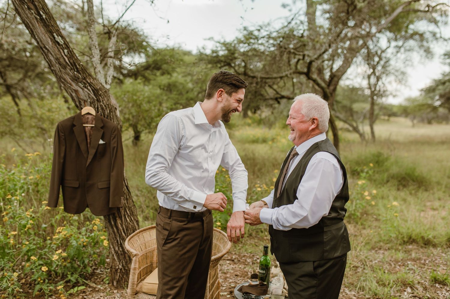 Two people having a conversation in a rustic outdoor setting with a suit jacket hanging nearby.