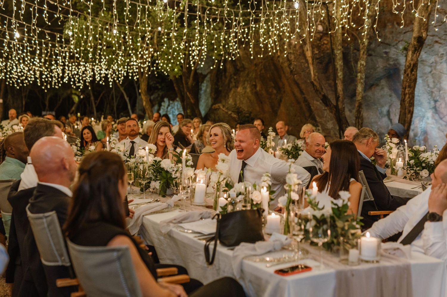 Elegant wedding reception tables adorned with floral centerpieces under glowing string lights.