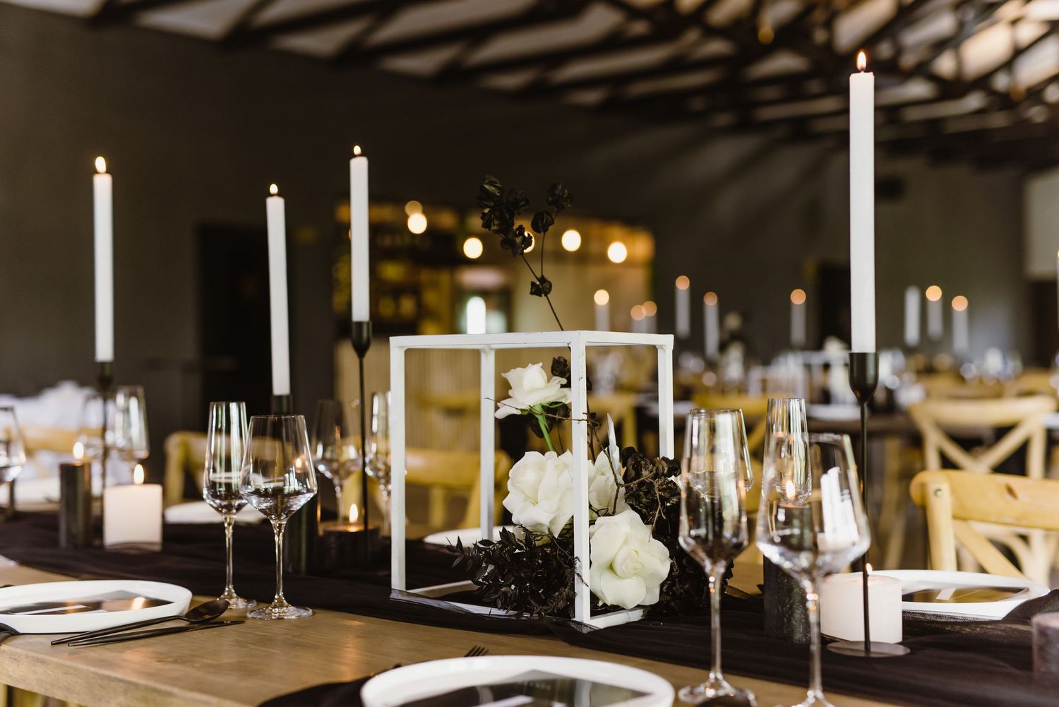 Elegant wedding reception tables set with minimalist white and black decor elements.