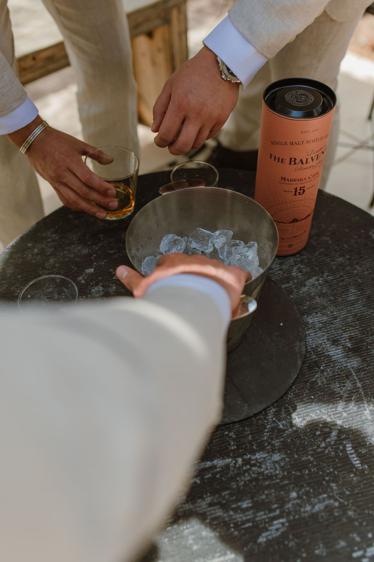 Close-up shots of hands pouring drinks over ice during wedding celebrations.