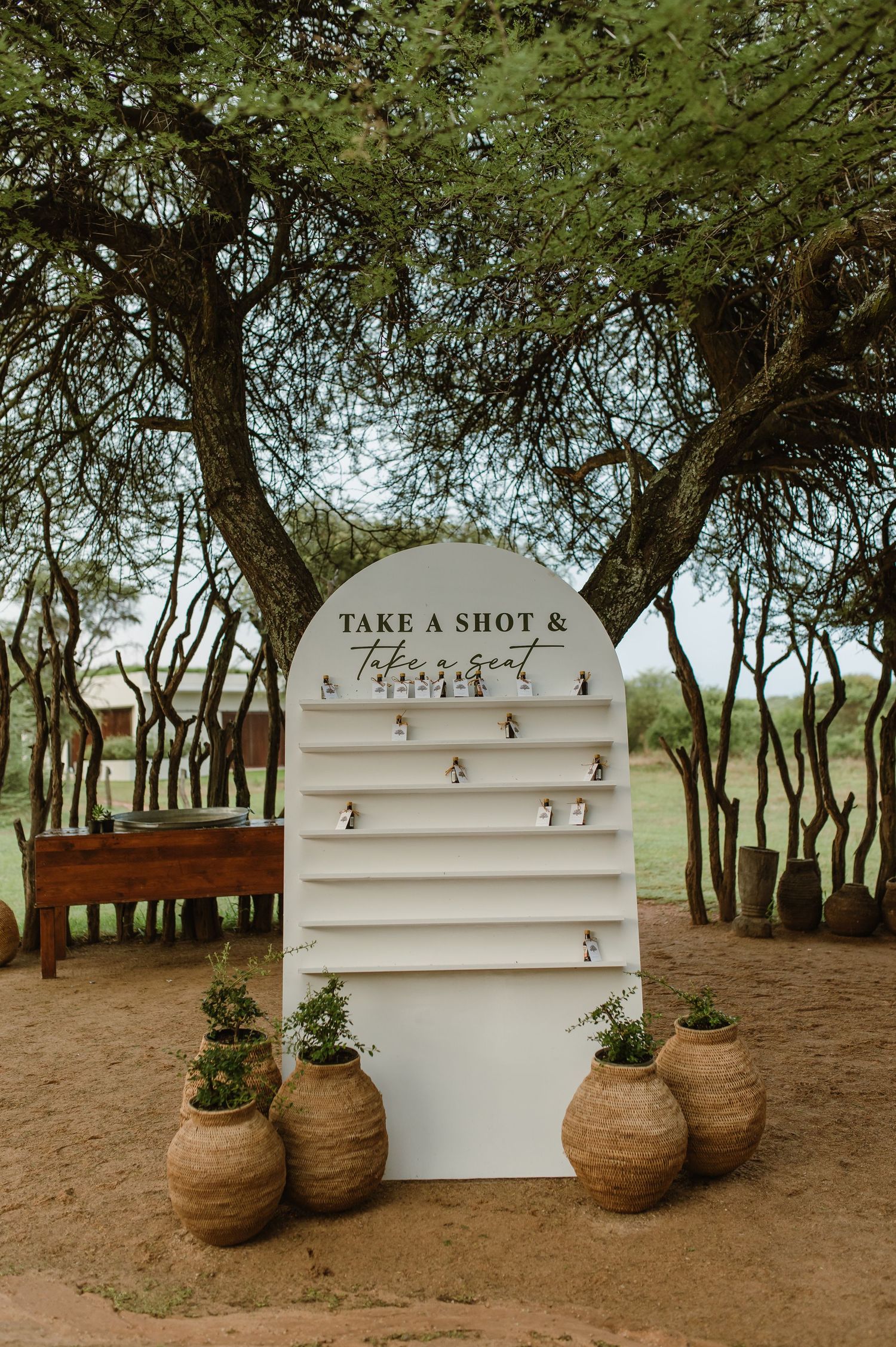 A rustic white shot display shelf with clay pots underneath in an outdoor setting.