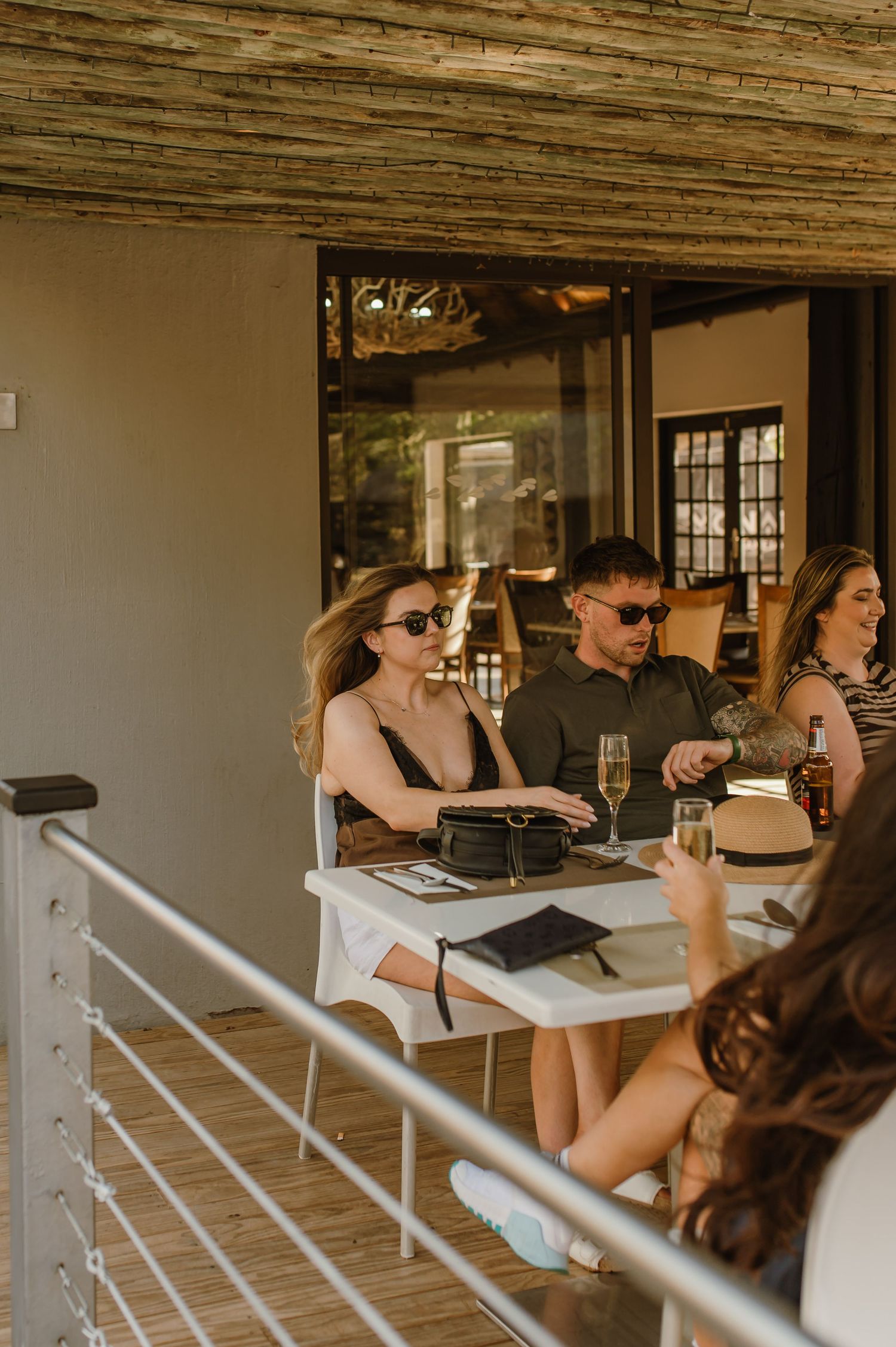 Guests seated at a covered outdoor dining area with natural lighting.