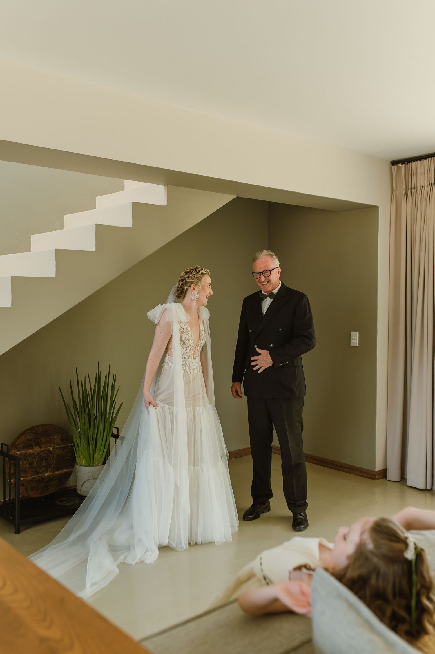 Emotional first look moment captured in modern minimalist interior with staircase.