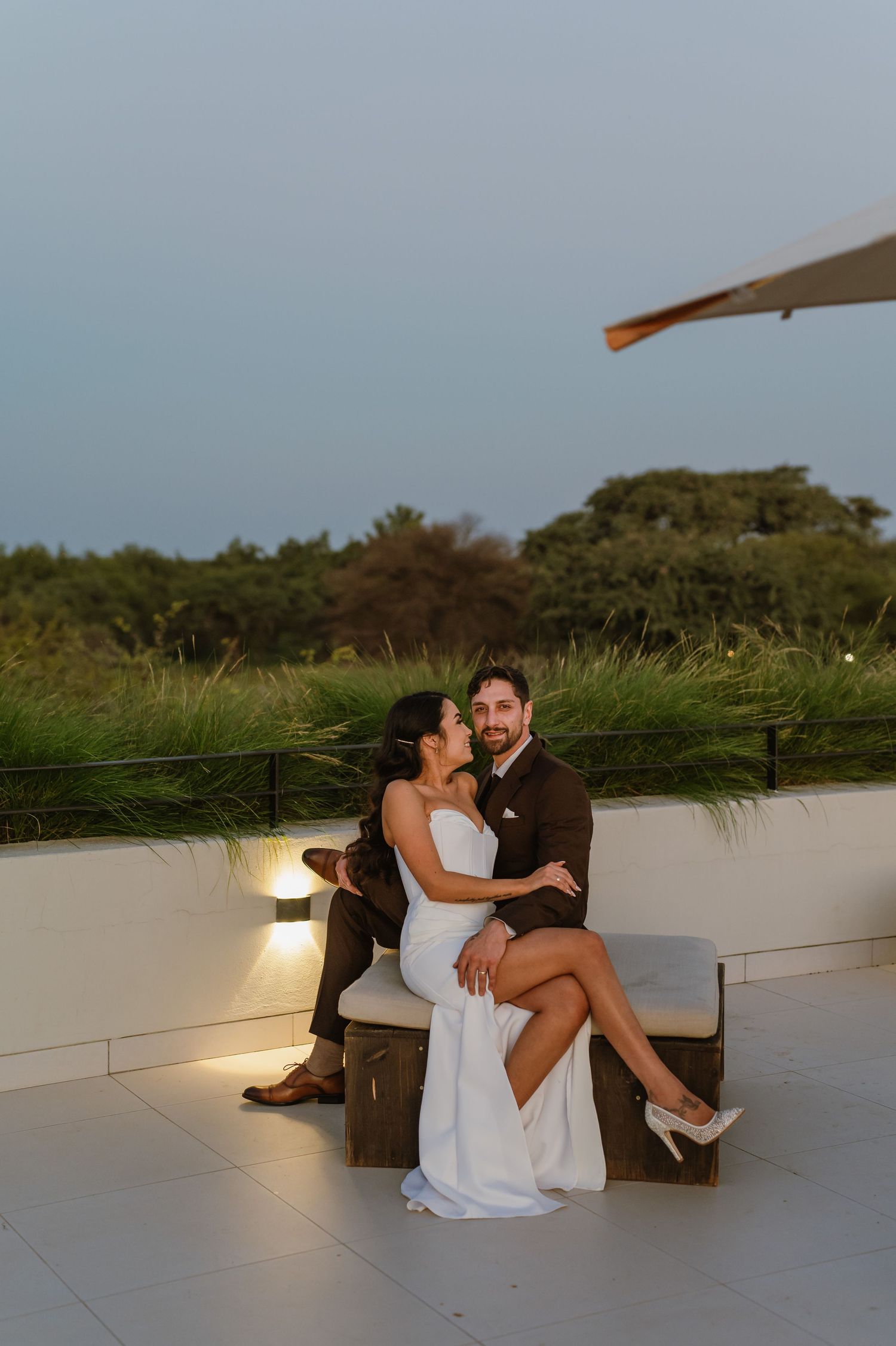 Couple in formal attire sitting together on illuminated outdoor terrace.