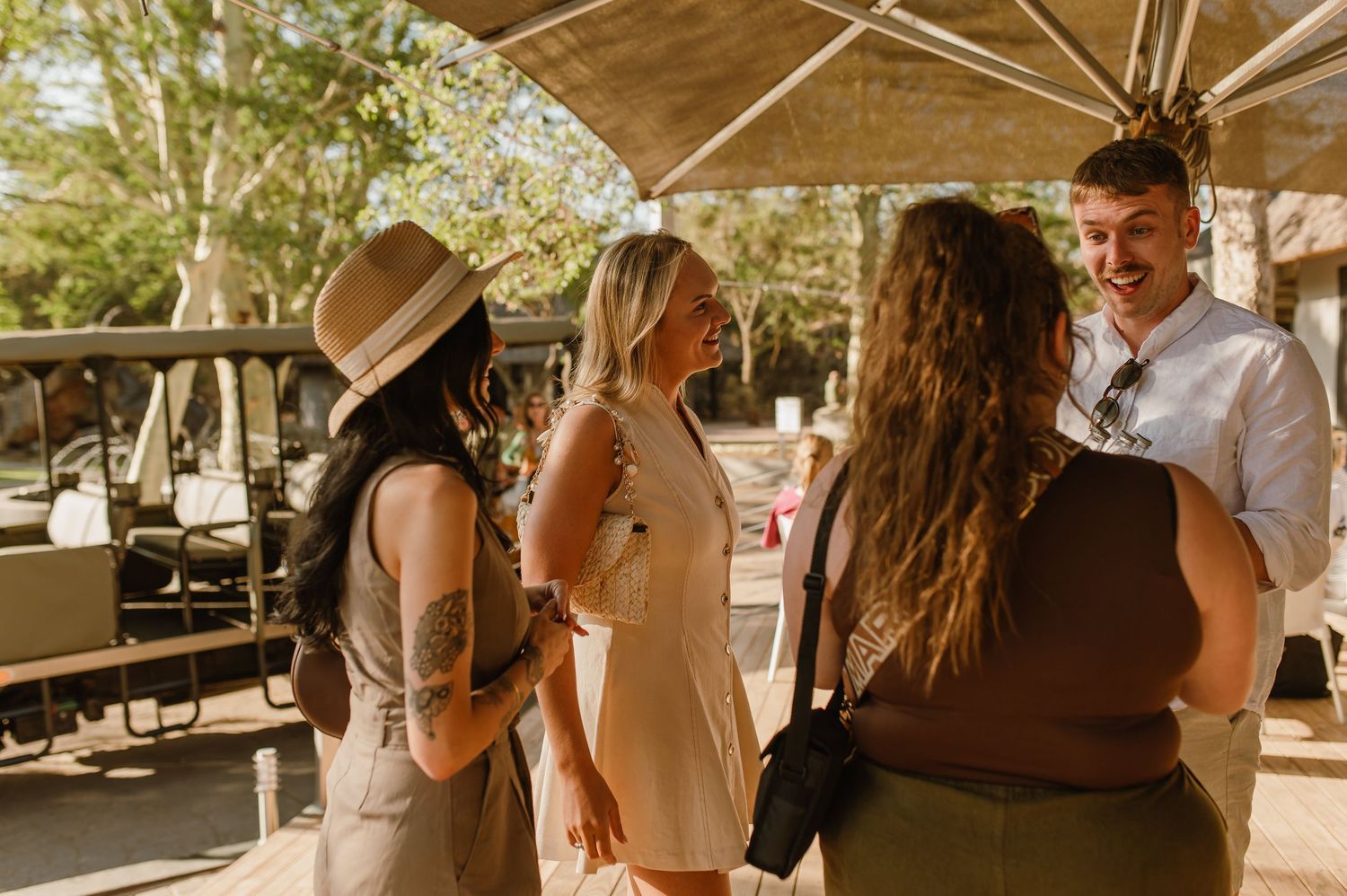 People gathering under a shaded outdoor structure during daytime.