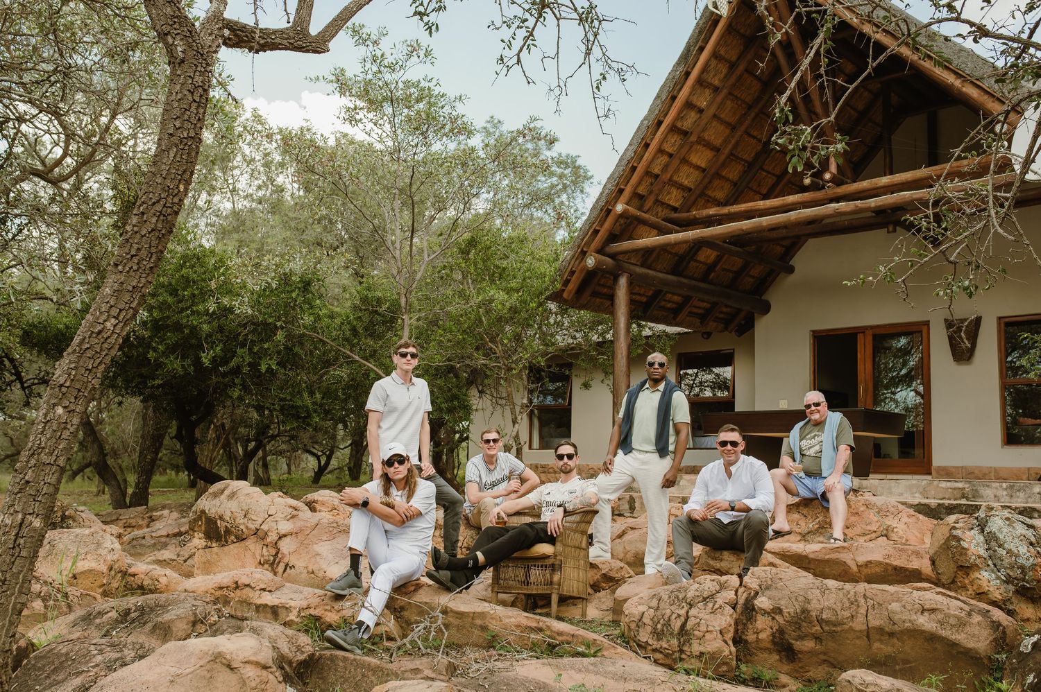 Rustic outdoor venue with thatched roof and stone walls nestled among trees.