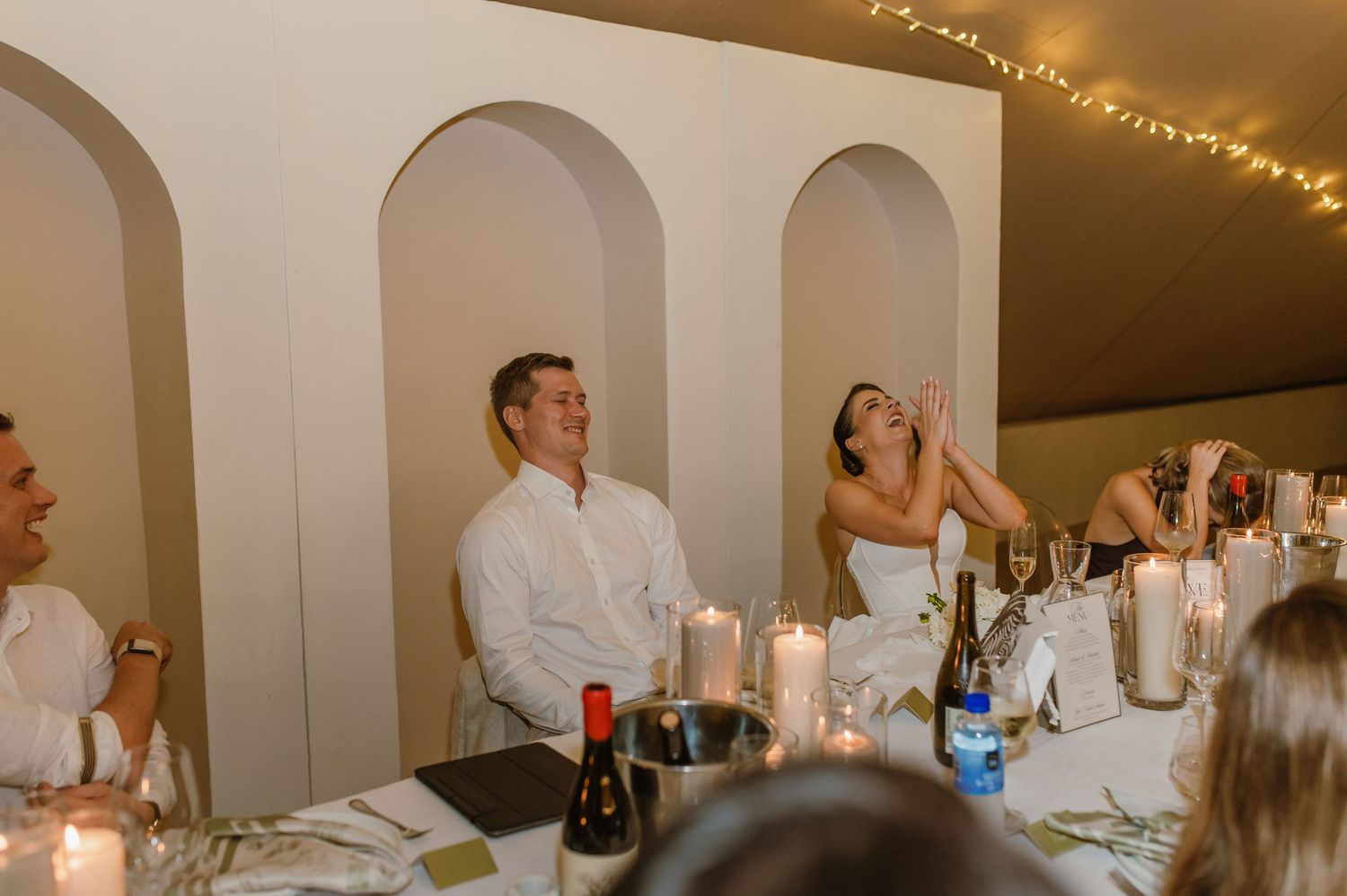 Indoor wedding reception with arched walls and string lights creating a warm ambiance.