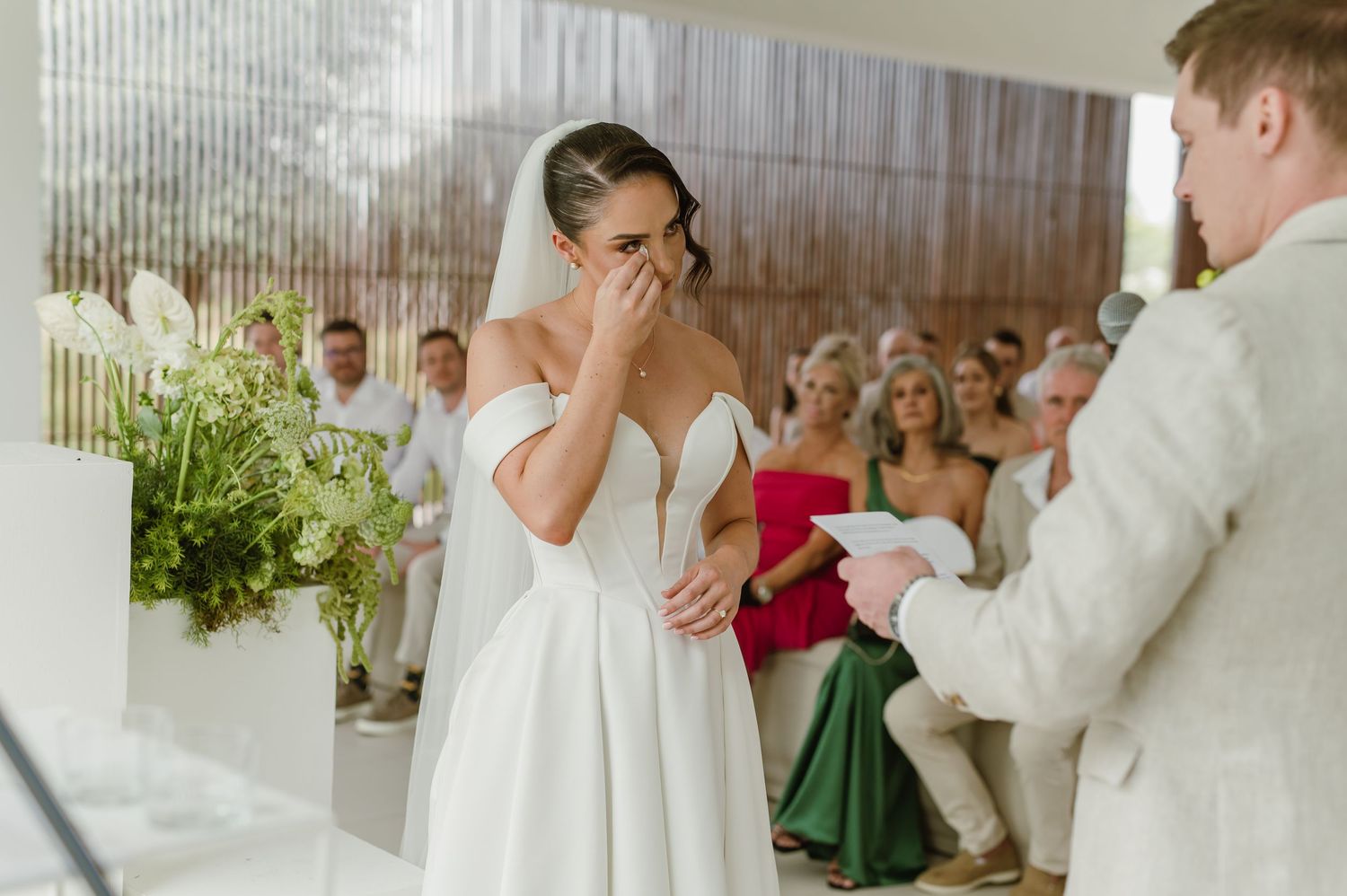 Wedding ceremony in progress in a bright white modern space with floral decorations.
