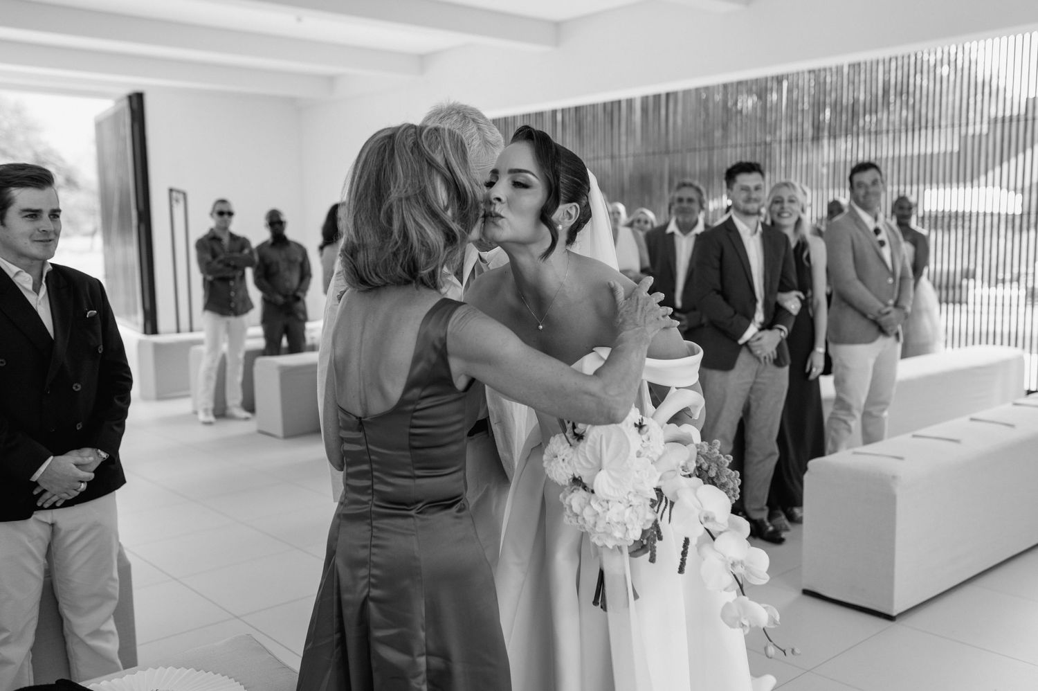 Wedding guests mingling in an elegant white interior space with modern decor.