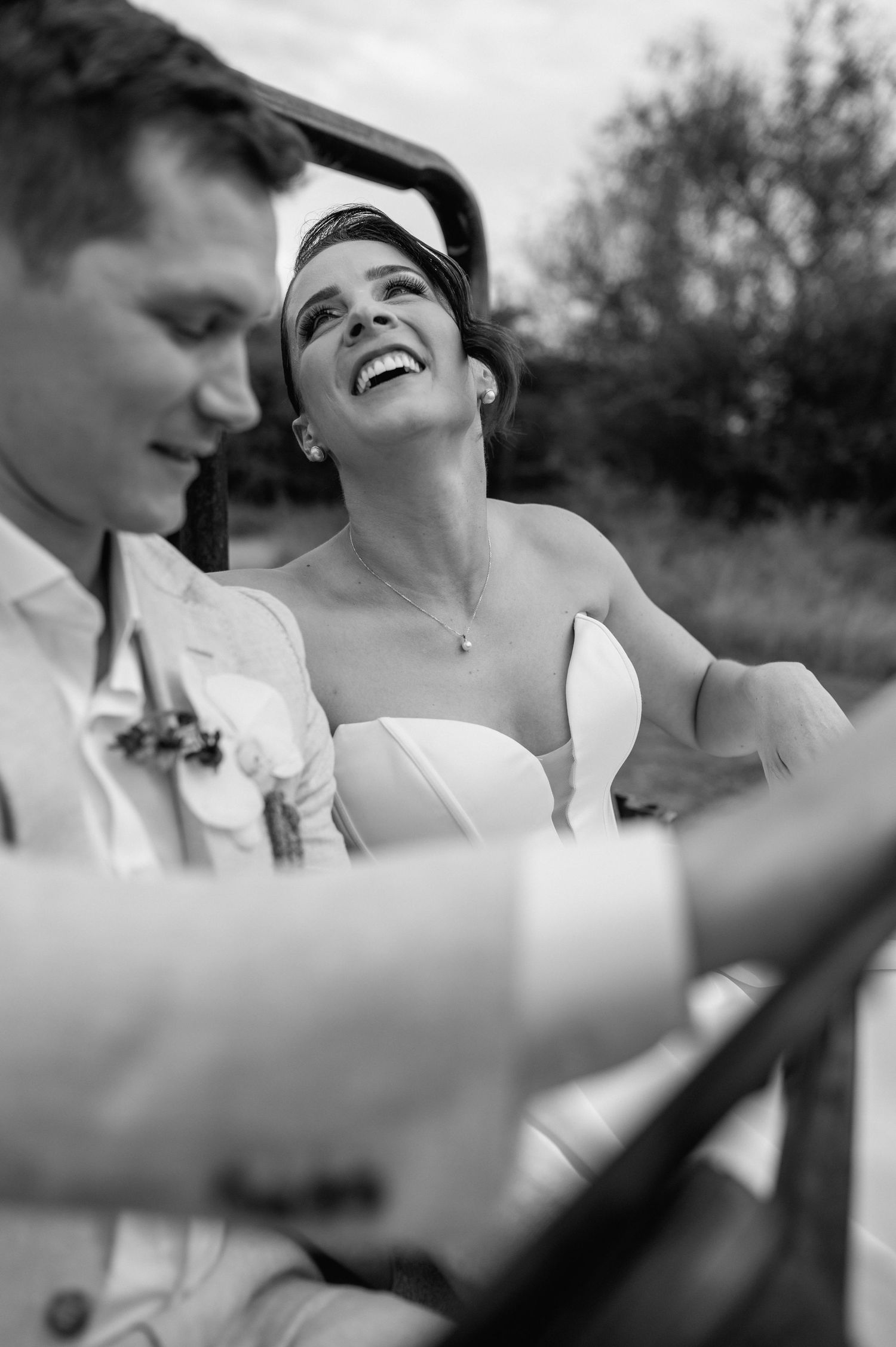 A candid black and white moment of joy captured during an outdoor wedding photoshoot.