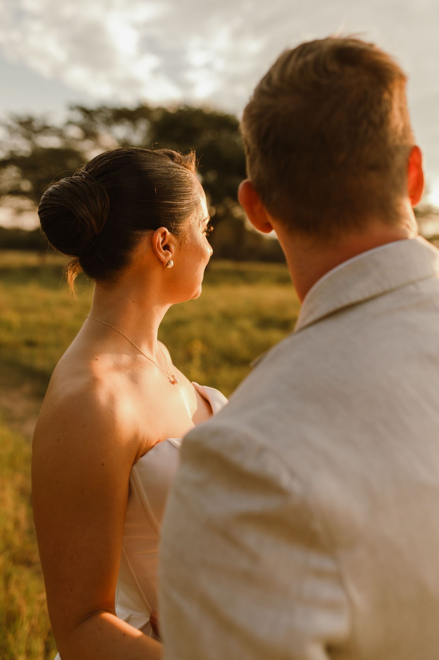 Romantic sunset wedding portraits showing intimate moments between the couple in a golden field.