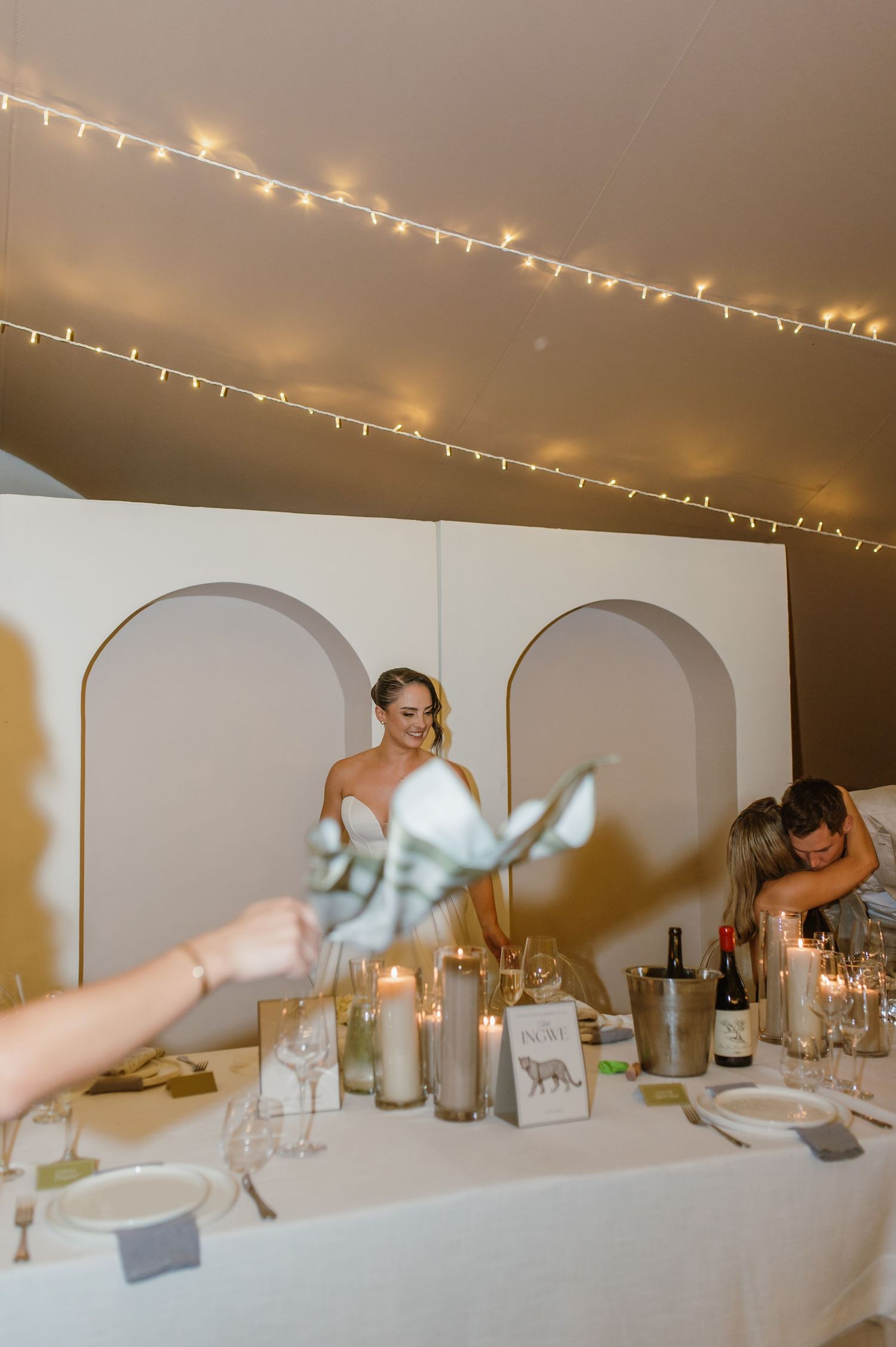 Reception table settings with candles and string lights creating a warm ambiance.