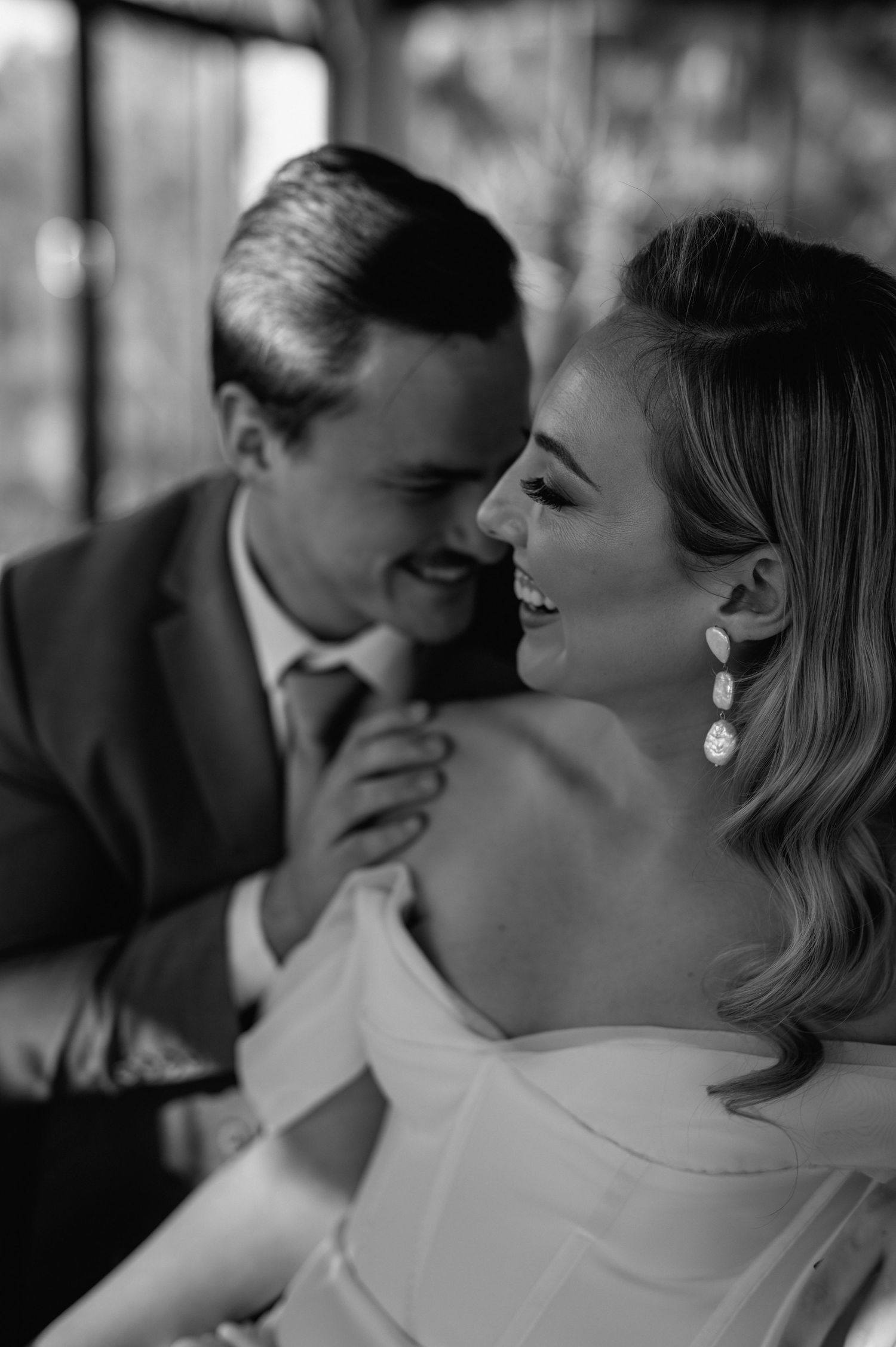 Intimate black and white portrait capturing tender moment between wedding couple.